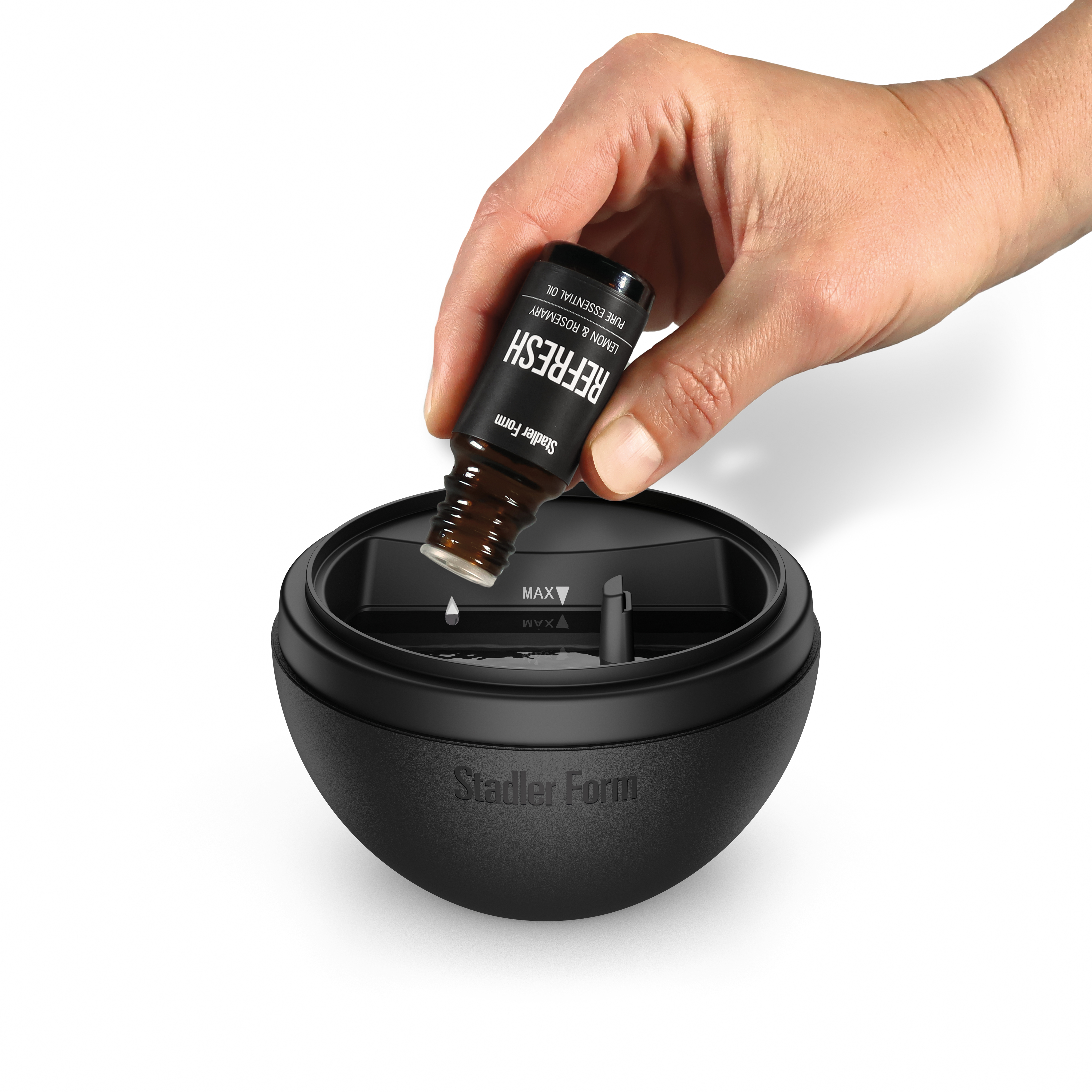 Eine Hand tropft Refresh-Öl in einen schwarzen Stadler Form Diffusor.