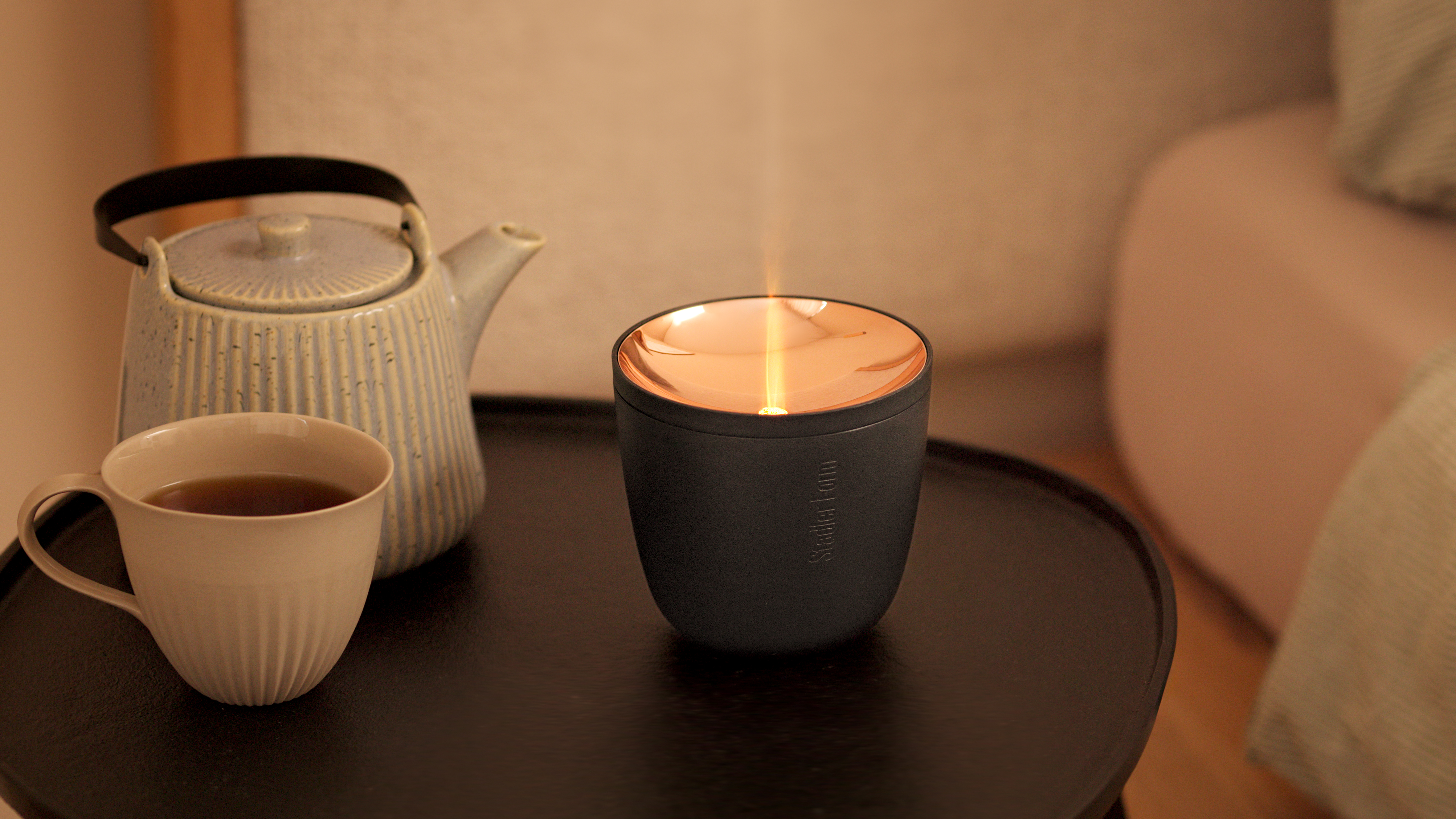 Ein diffuser erzeugt feinen Dampf auf einem Tisch neben Teekanne und Tasse.