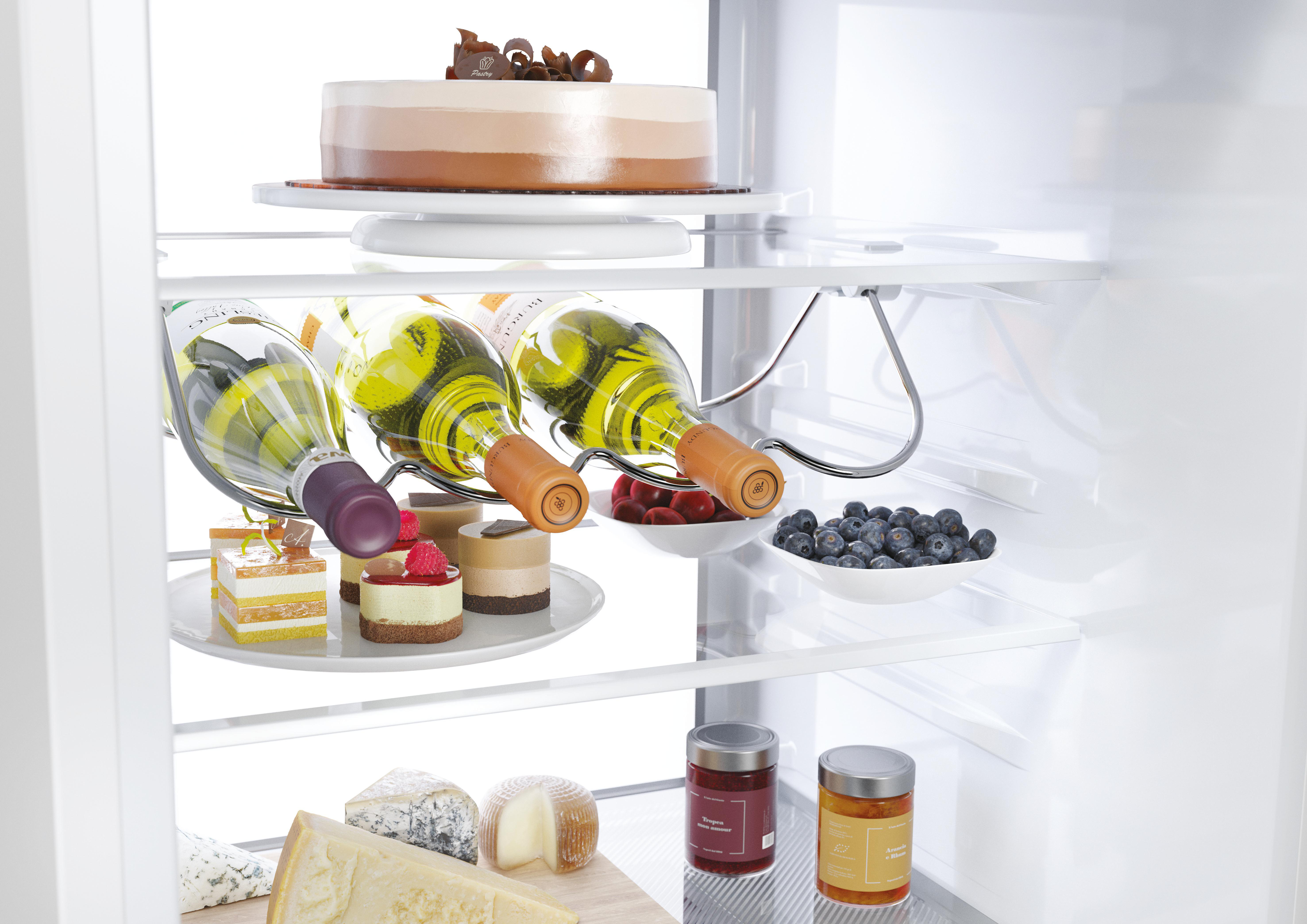 Ein weißer Kühlschrank gefüllt mit Kuchen, Wein, Beeren, Käse und Gläsern.