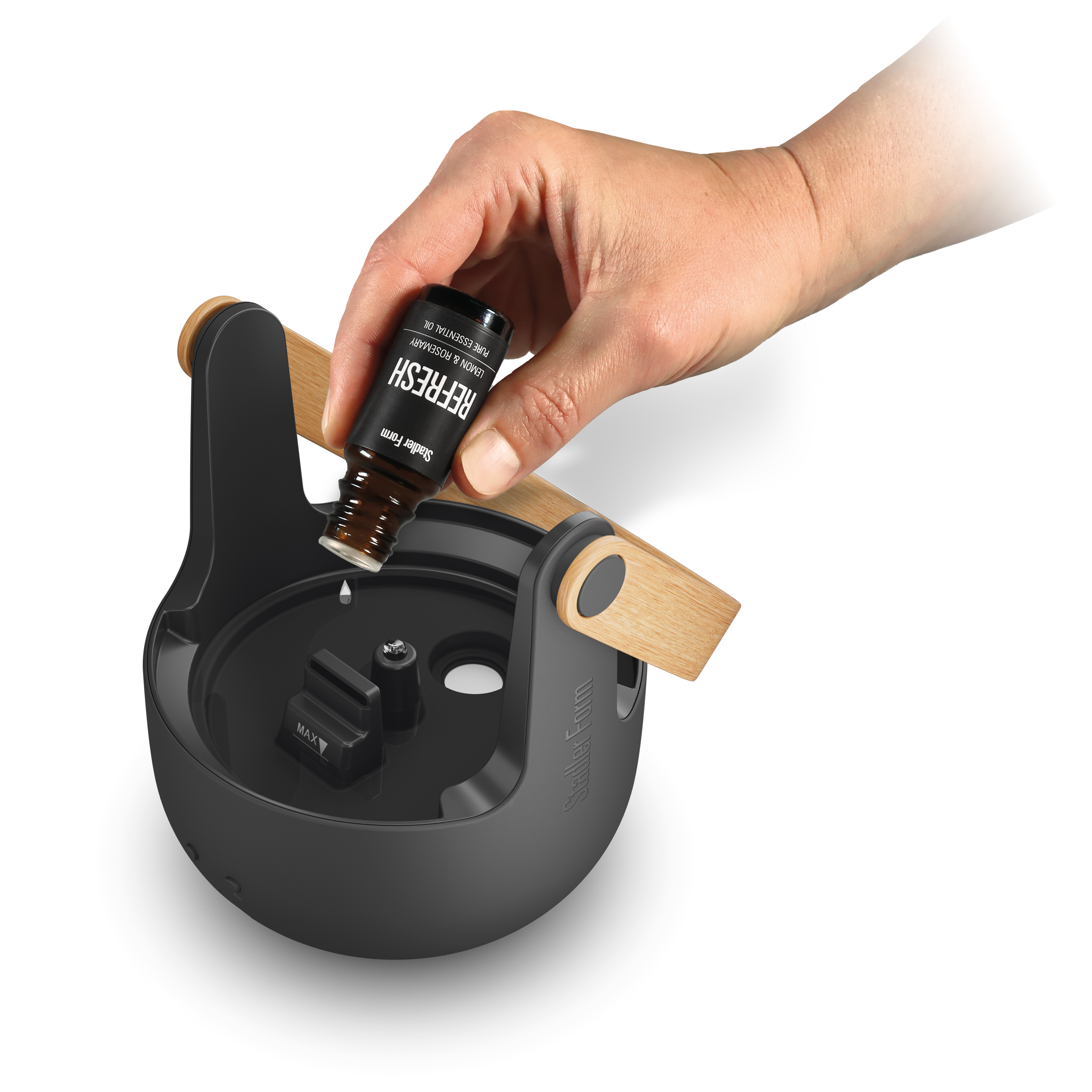 Hand tropft ätherisches Öl in einen schwarzen Diffusor.