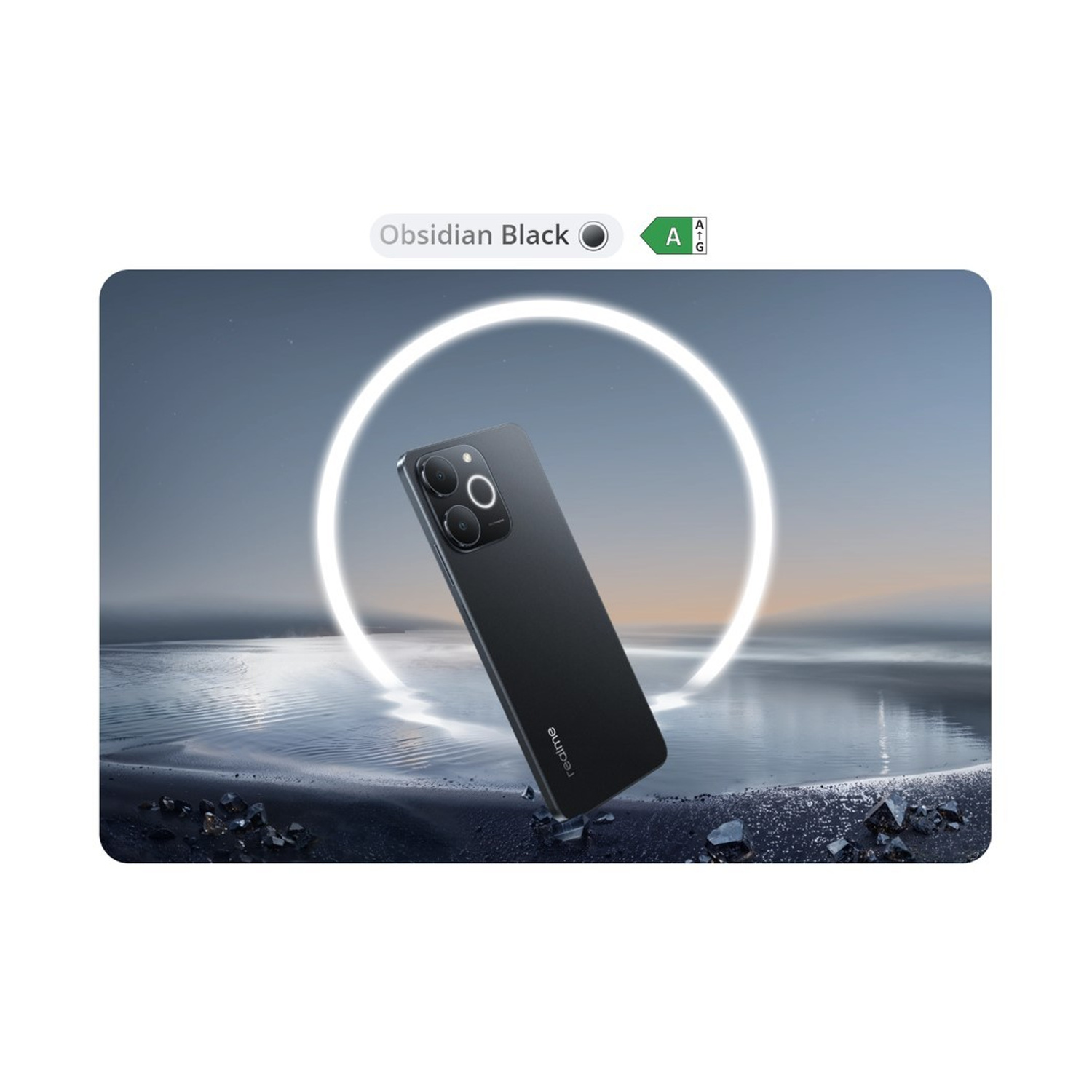 Uno smartphone nero si trova su una spiaggia sassosa davanti a un anello luminoso e all'acqua al crepuscolo.