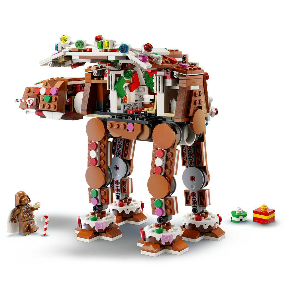 Eine Lego-Ingwerbrot-AT-AT-Figur stehend mit Weihnachtsdekoration, einem Vader-Minifigur und kleinen Geschenken.