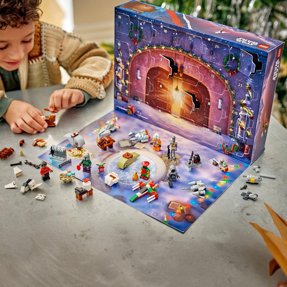Ein Kind spielt mit einem Star Wars Lego Adventskalender, dessen geöffnete Türchen diverse Minifiguren und Modelle zeigen.