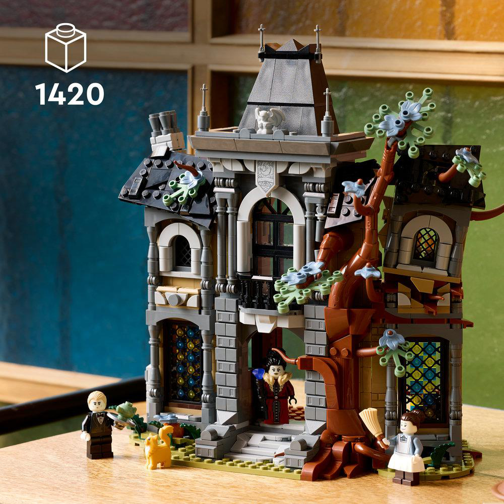 Ein detailliertes Lego Spukschloss mit grauen Steinmauern, Bogenfenstern, einem Baum und Minifiguren.