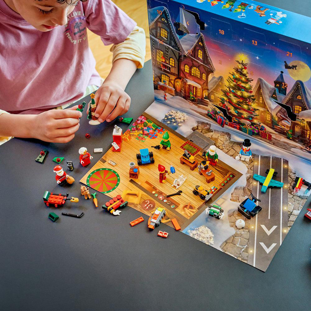 Ein Kind öffnet einen Lego-Weihnachtskalender und baut kleine Spielzeuge auf einem Tisch auf.