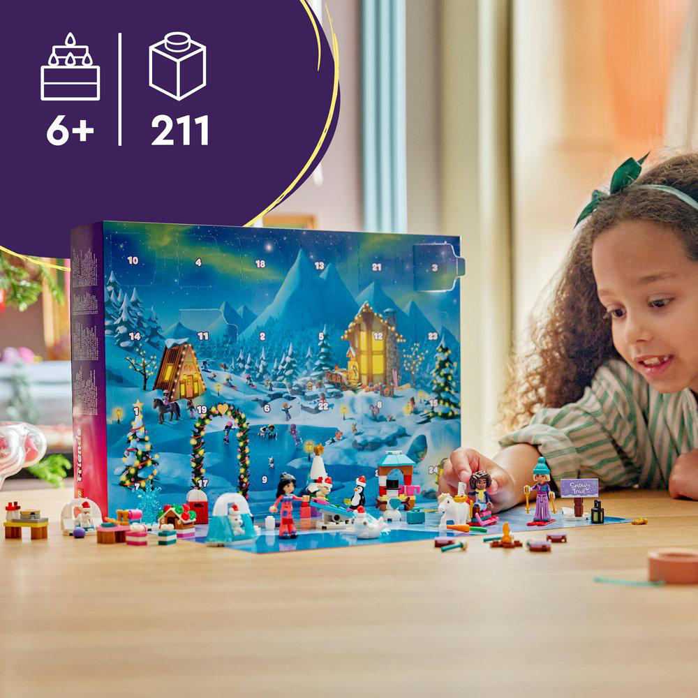 Ein Mädchen lächelt, während es mit einem Lego Friends Adventskalender und bunten Bausteinen auf dem Tisch spielt.