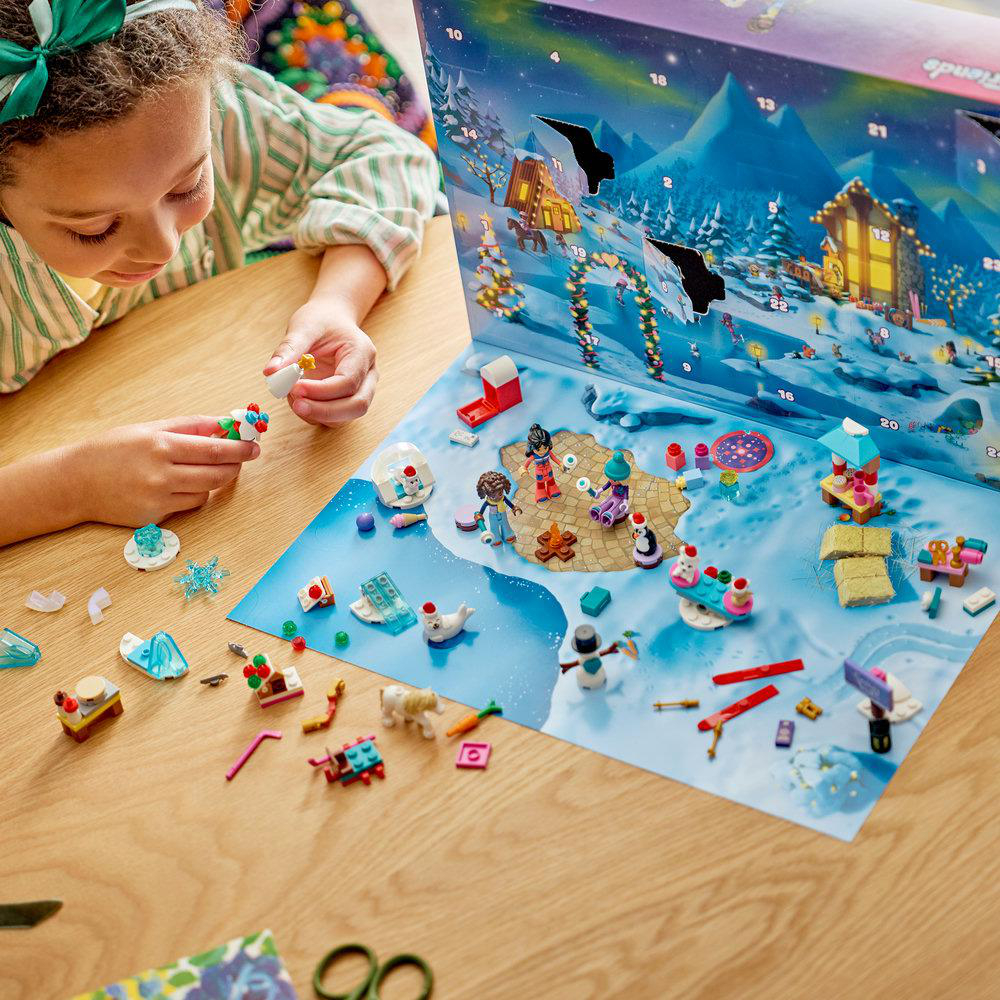 Ein Kind baut ein Lego Friends Adventskalender-Spielset auf einem Holztisch auf.