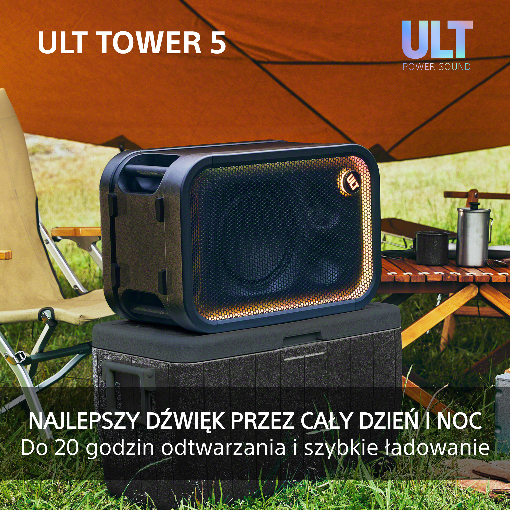 Czarny głośnik ULT TOWER 5 stoi na lodówce turystycznej na trawiastym kempingu.