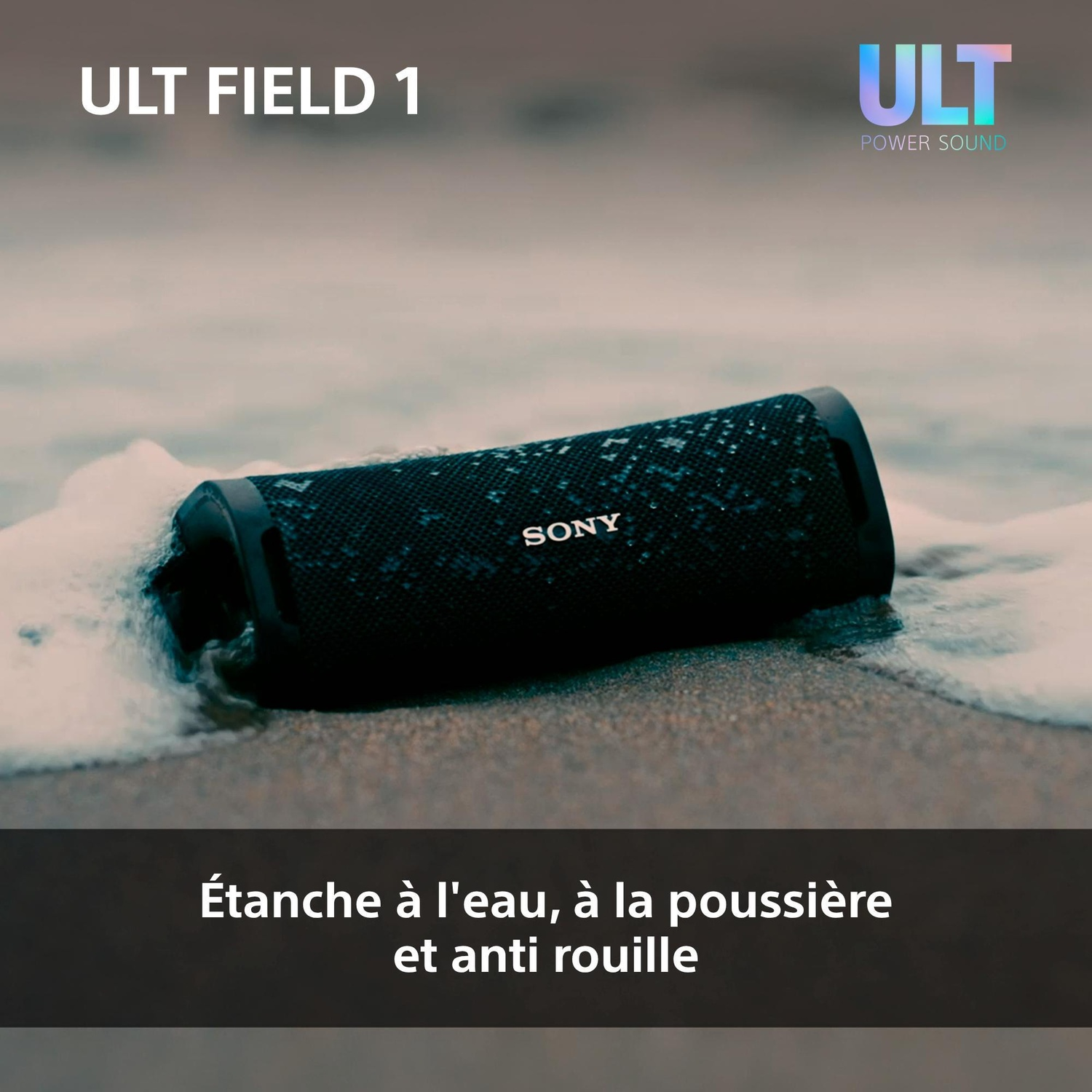 Un haut-parleur portable Sony noir repose sur une plage de sable près de l'écume de mer.