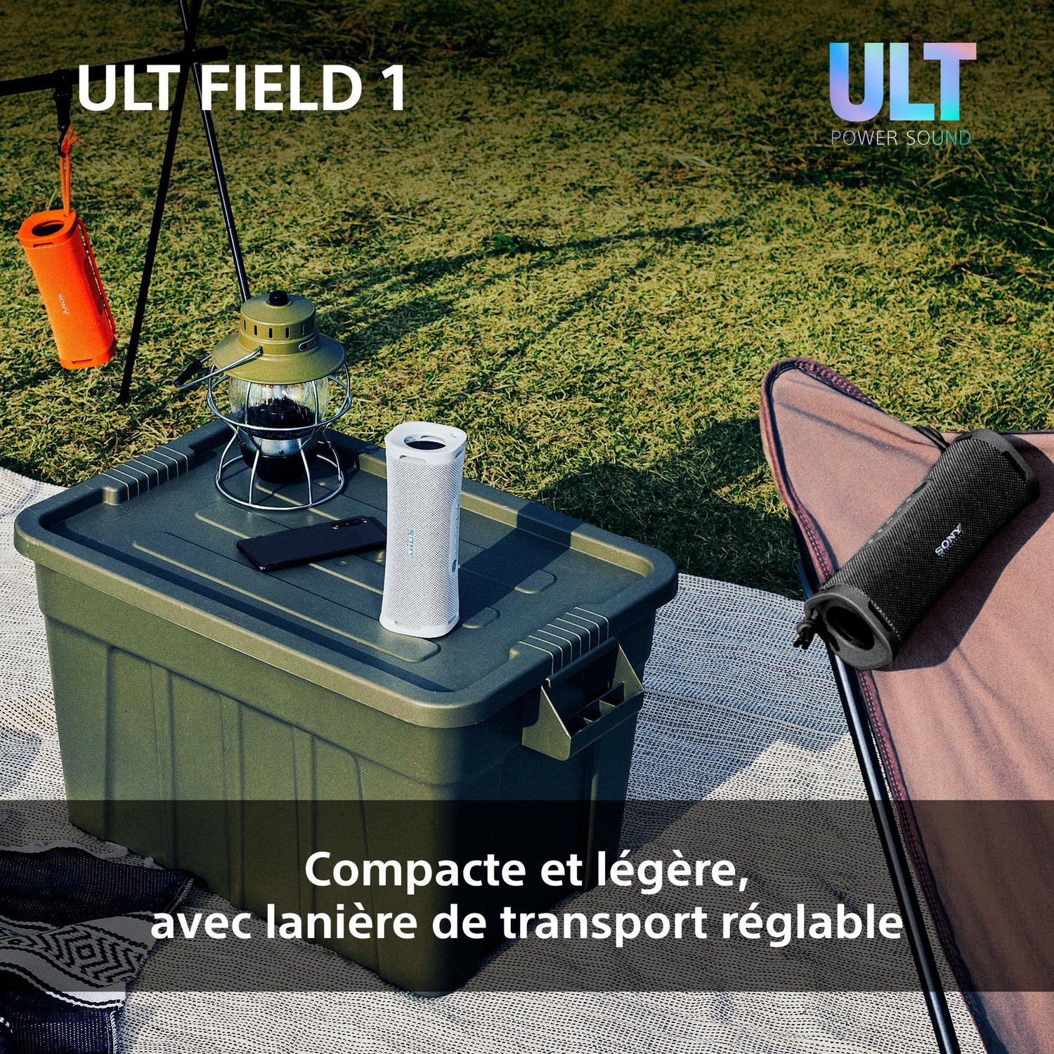 Une enceinte blanche ULT Field 1 sur une boîte verte en plein air, avec une lanterne et un smartphone.