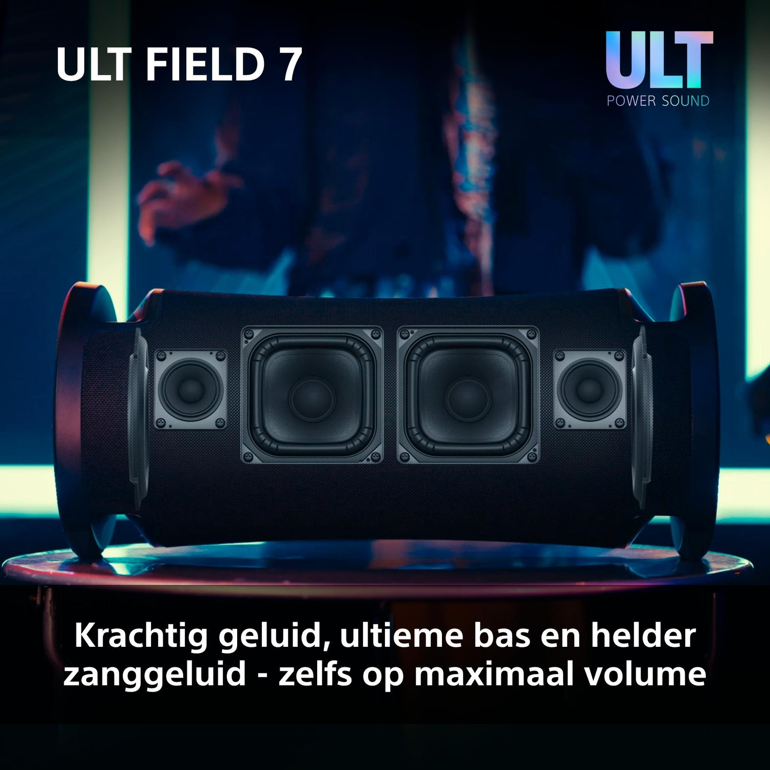 Black ULT FIELD 7 speaker on an illuminated stage in front of a blue and white backdrop.