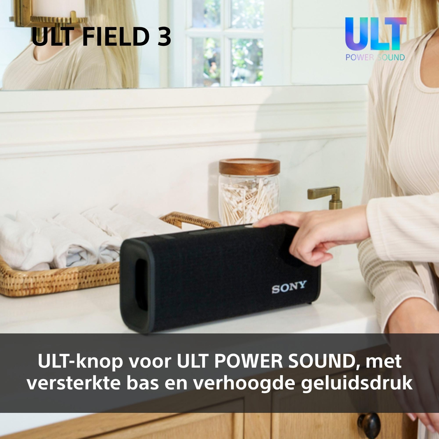 Een vrouw drukt op een knop van een zwarte Sony-speaker op een badkamermeubel.