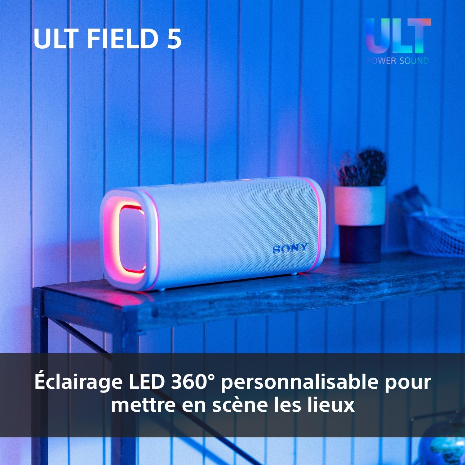 Un haut-parleur Sony blanc avec des LED rouges lumineuses est posé sur une table en bois.