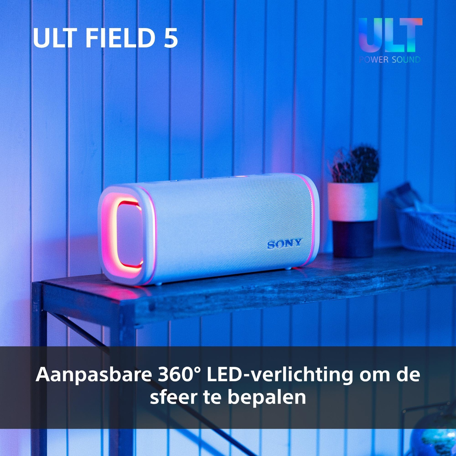 A white Sony Bluetooth speaker with reddish LED lighting sits on a shelf in front of a blue wall.