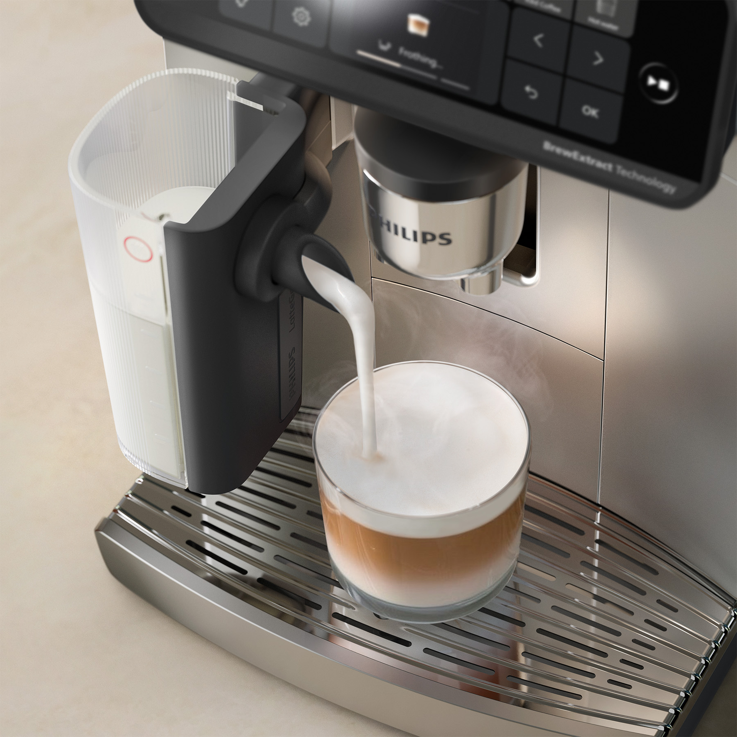 An espresso machine pours milk into a layered coffee glass on a steel drip tray.