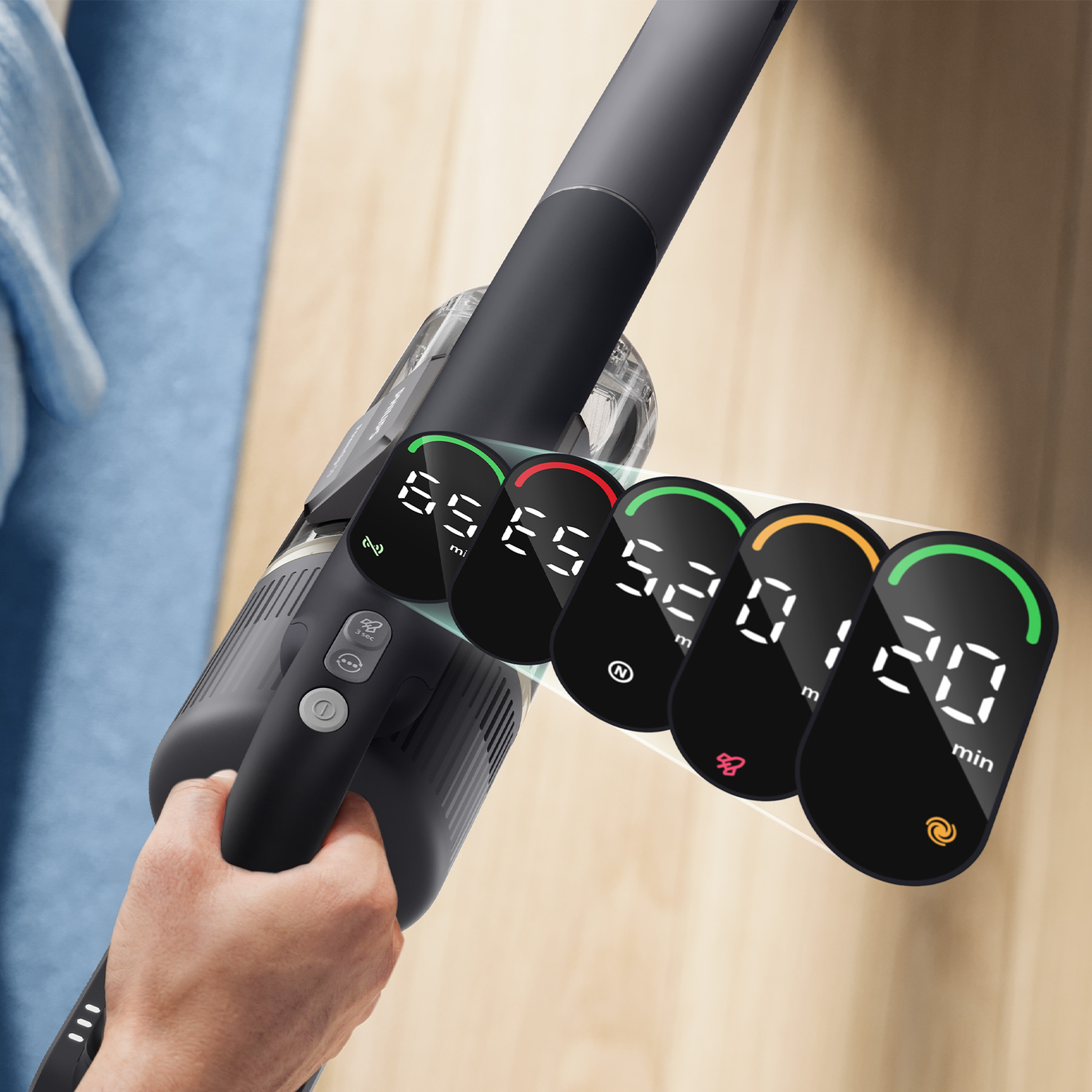 Hand holds a vacuum cleaner with five digital displays showing various battery levels and settings.
