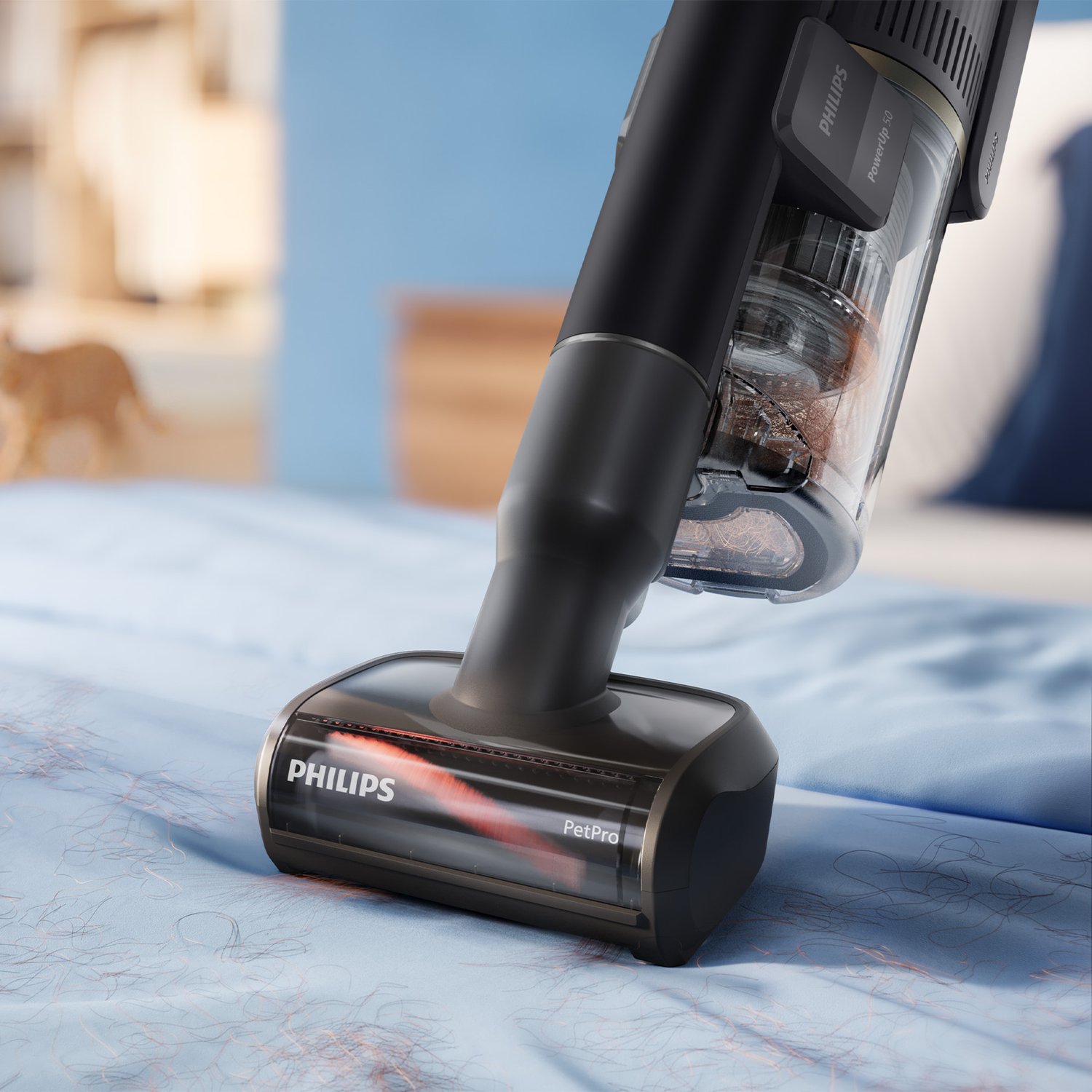 A black Philips PetPro vacuum cleaner cleans pet hair from a blue bedsheet.