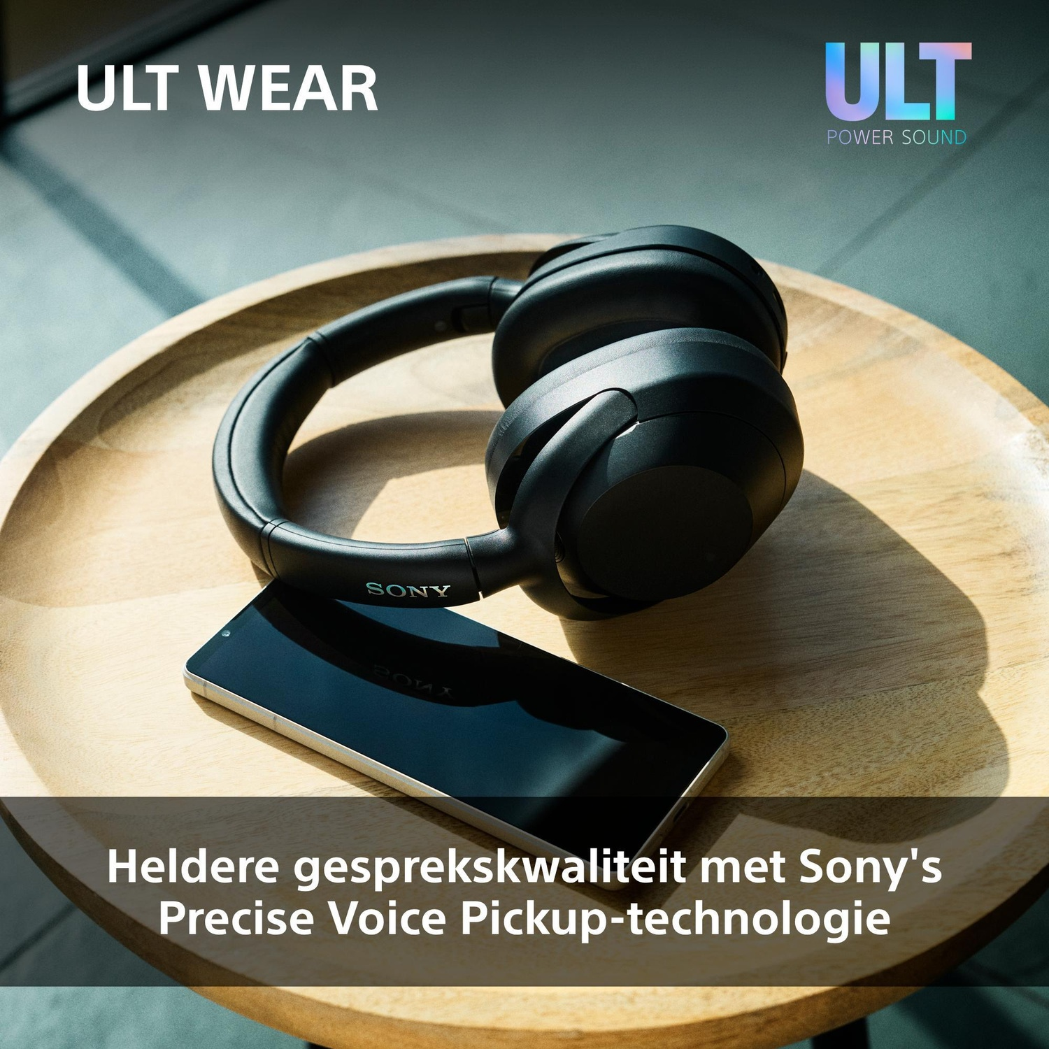 Black Sony headphones and a smartphone on a round wooden table.