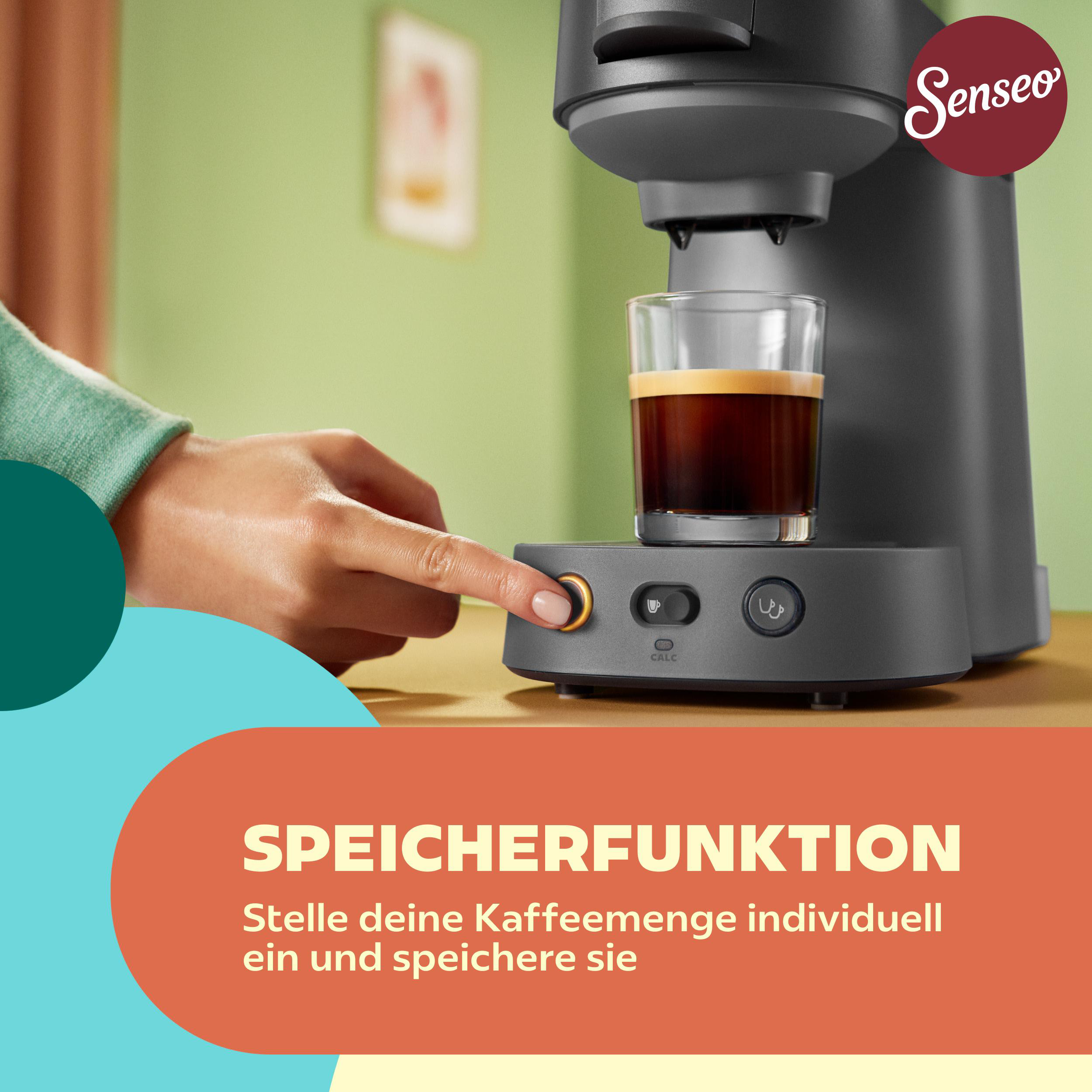 Hand drückt einen goldenen Knopf an einer grauen Senseo-Kaffeemaschine mit einer Glas Tasse Kaffee.