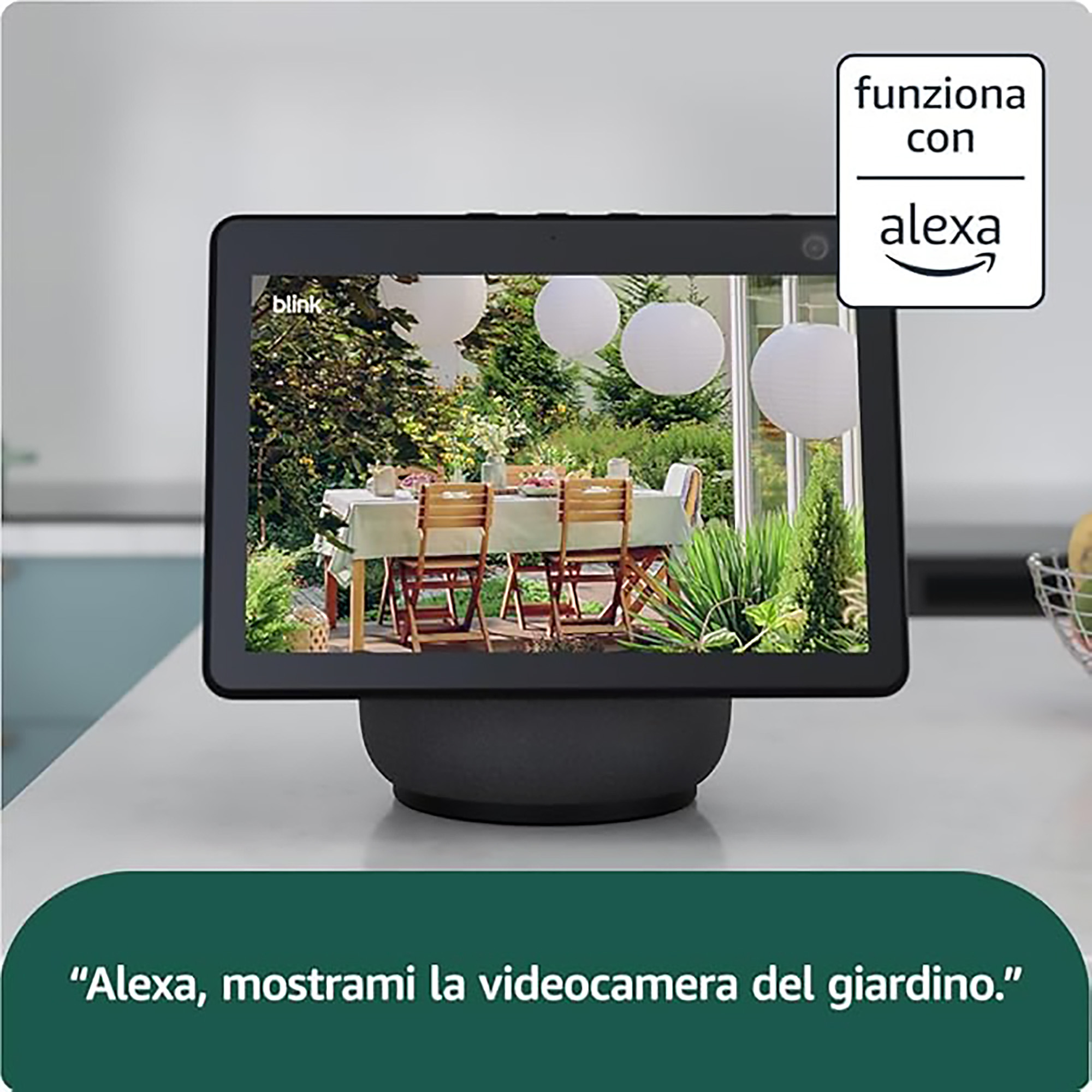 Uno schermo smart su un tavolo mostra un giardino con tavolo da pranzo. In alto a destra c'è scritto Funziona con Alexa.