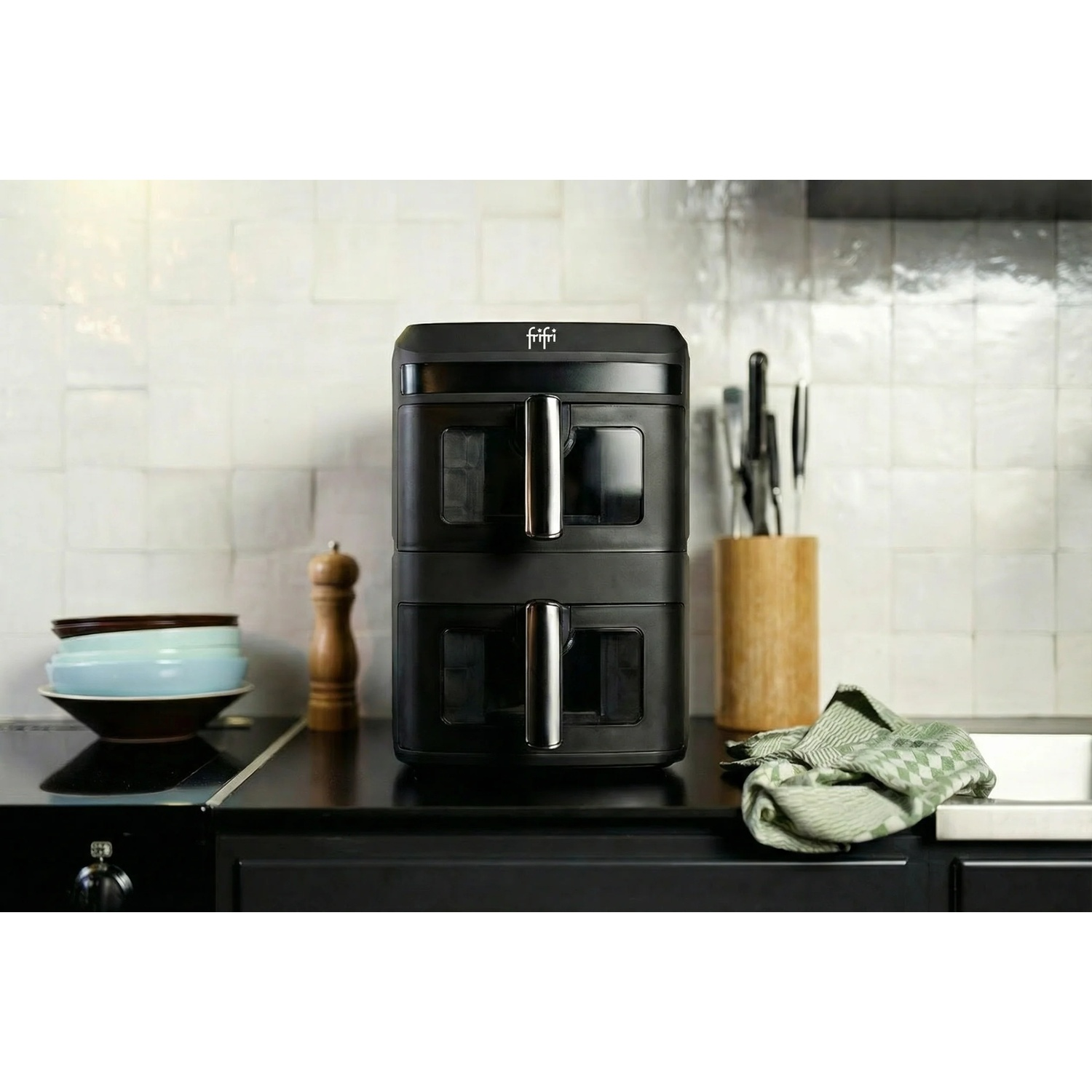 A black double air fryer sits on a kitchen counter with a tiled wall backdrop.