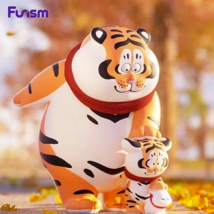 Eine große und eine kleine Tiger-Figur im Cartoon-Stil stehen im Herbstlaub.