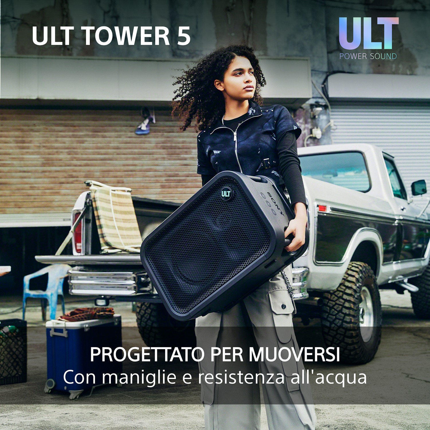 Una donna tiene in mano un grande altoparlante Sony nero davanti a un pick-up bianco, con testo.