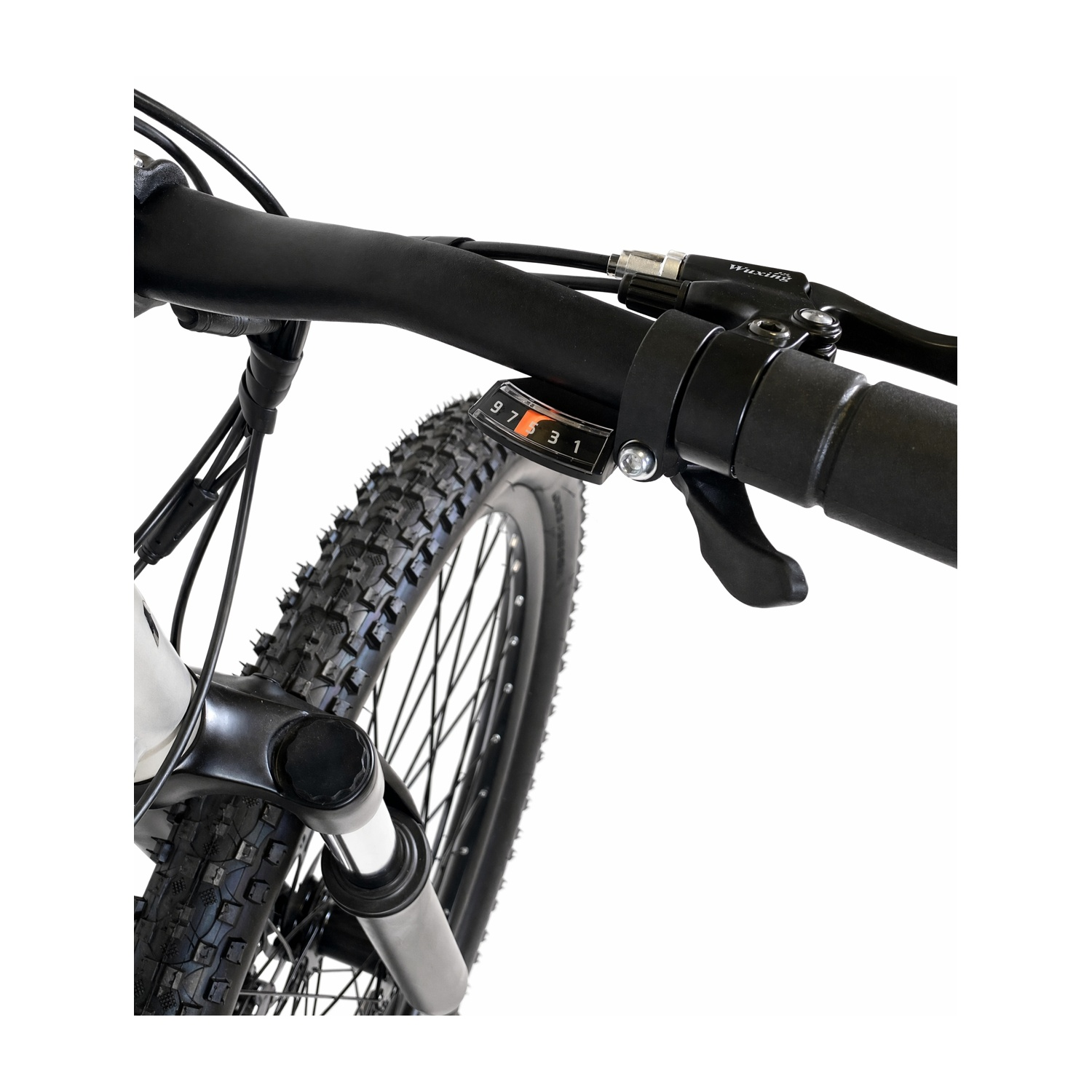 Primo piano del manubrio nero, del cambio e della ruota anteriore di una mountain bike.