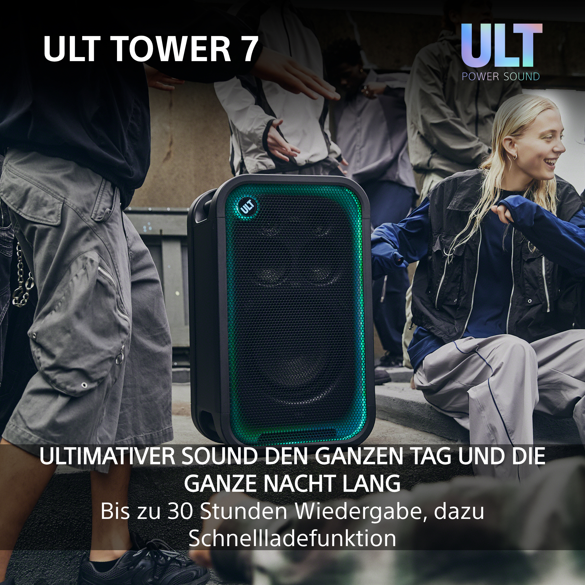 Ein schwarzer ULT TOWER 7 Lautsprecher mit grünem Licht steht draußen, umgeben von tanzenden Jugendlichen.