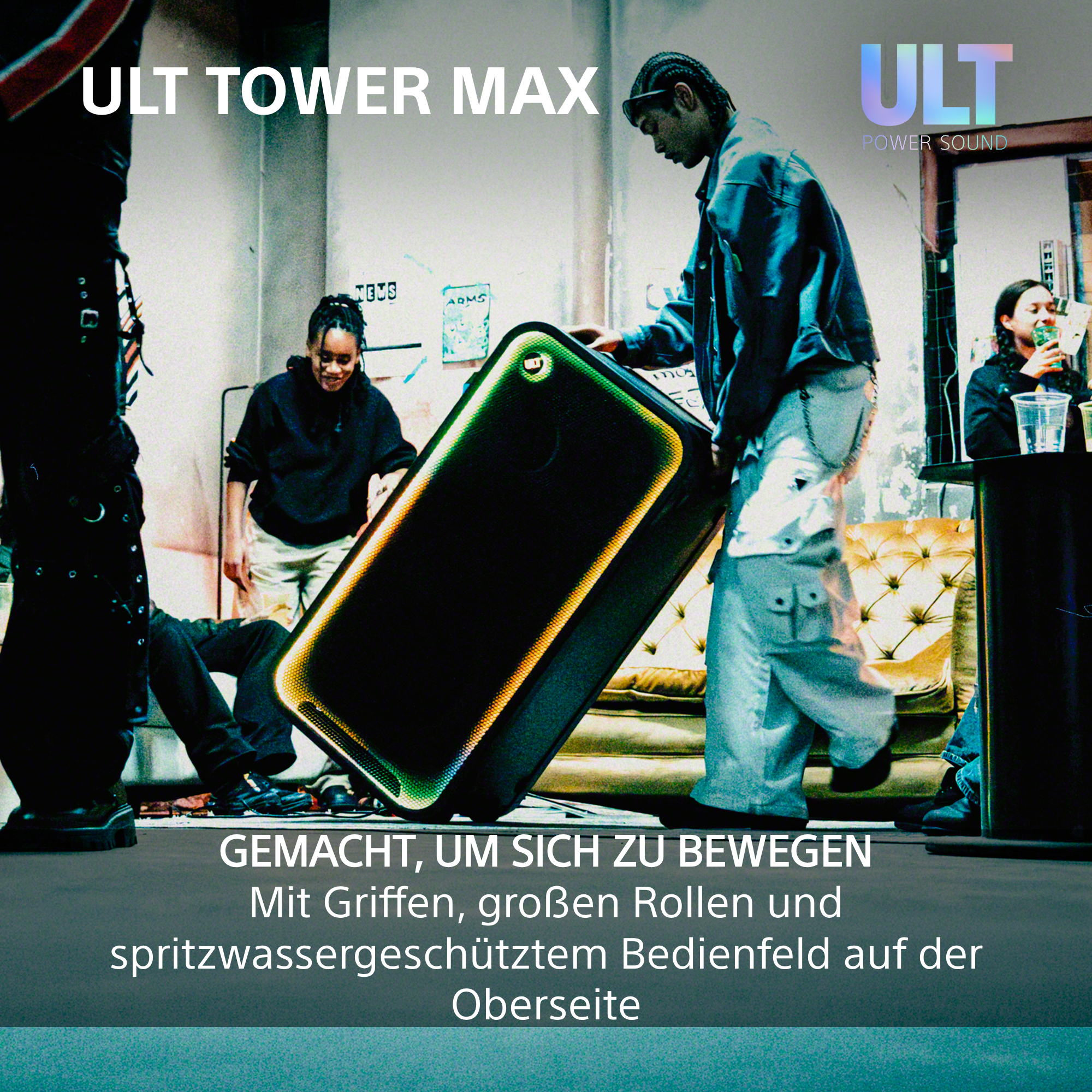 Ein Mann bewegt einen großen ULT TOWER MAX Lautsprecher in einem Raum mit anderen Personen.