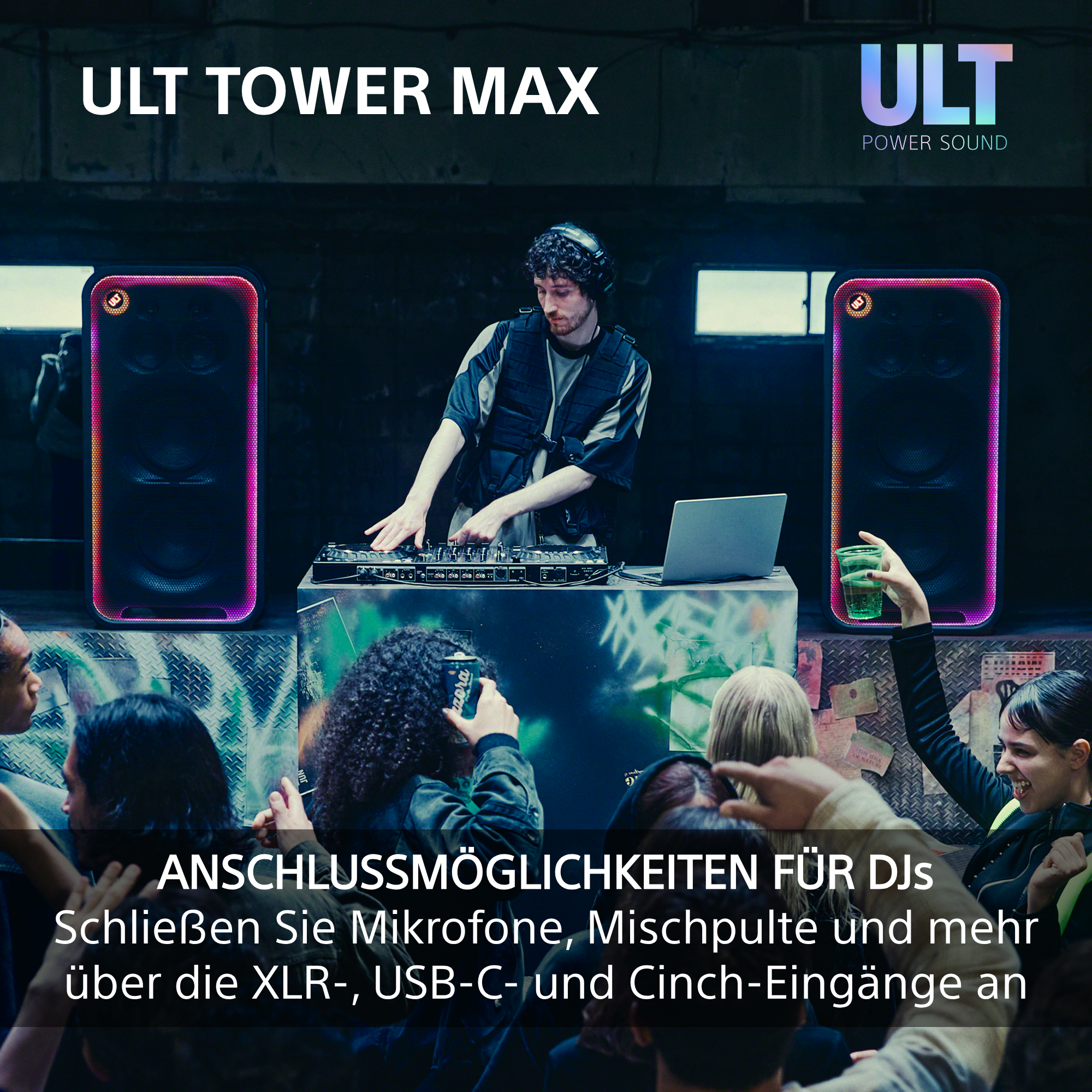 DJ steht vor Mischpult in einem Club, flankiert von zwei großen, beleuchteten Lautsprechern.