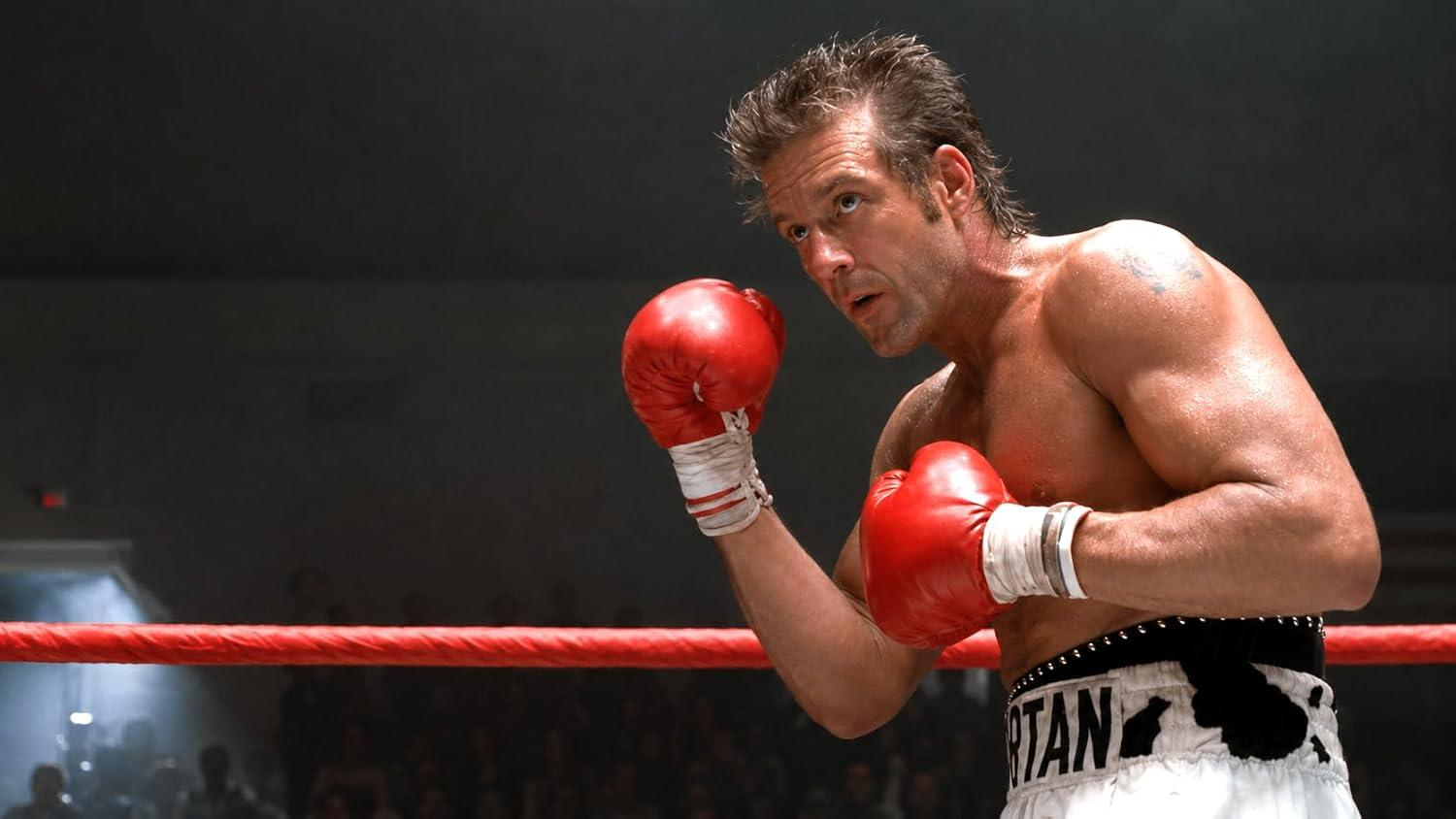 Ein Boxer mit roten Handschuhen in einem Ring schaut konzentriert.