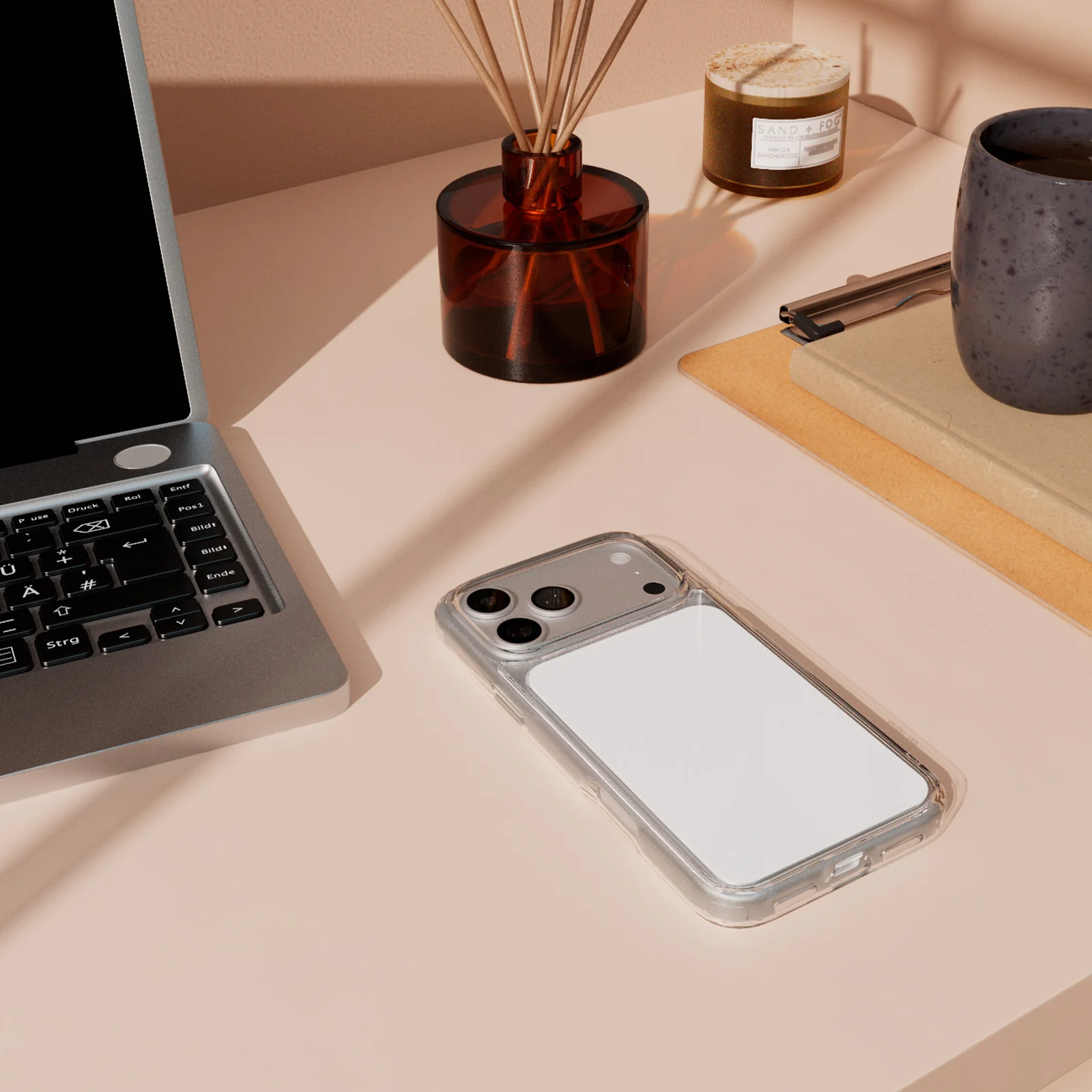 Ein ordentlicher Schreibtisch mit Laptop, Smartphone, Duftstäbchen, Notizbuch und einer Tasse.