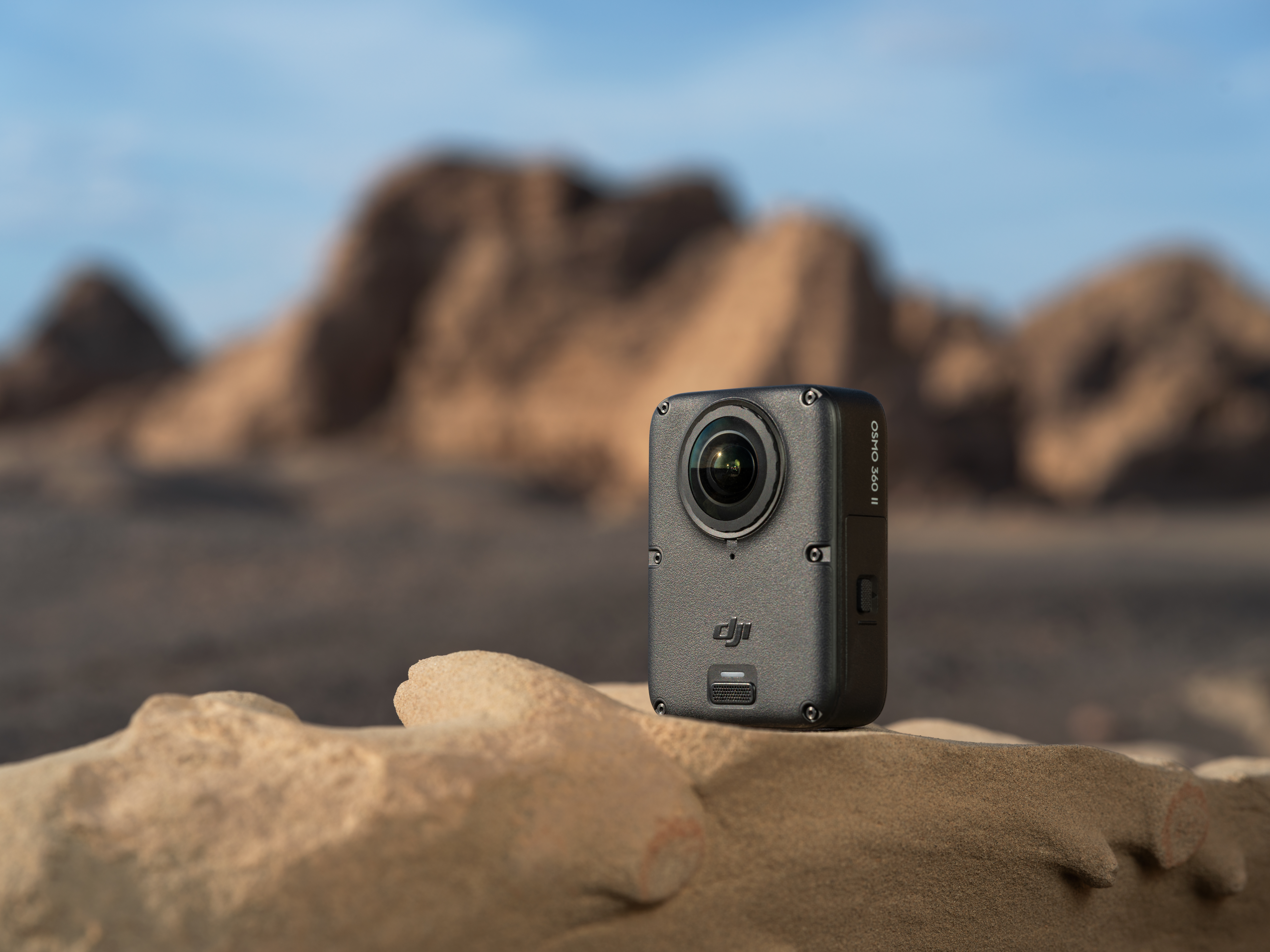 Eine schwarze DJI-Kamera steht auf einem Felsen vor einer unscharfen Bergkulisse.