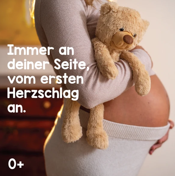 Eine schwangere Frau hält einen kleinen Teddybären vor ihrem Bauch. Text im Bild.