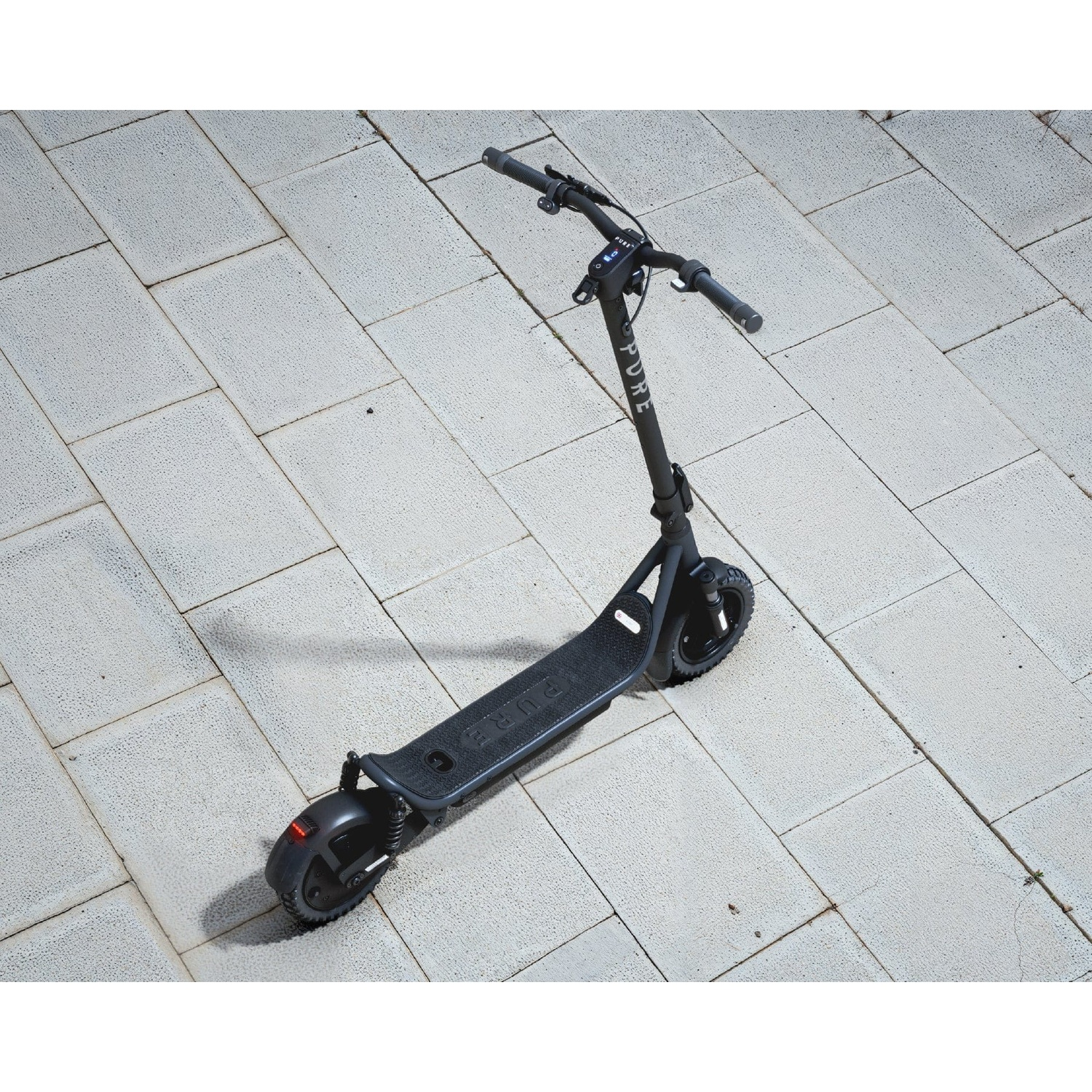 A black electric scooter standing on a light-colored tiled pavement.
