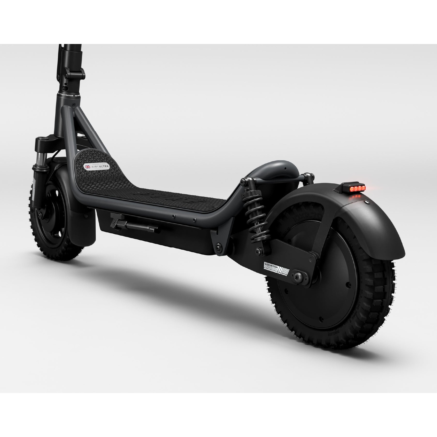 A black electric scooter with suspension springs, knobby tires, and a rear red light against a white background.
