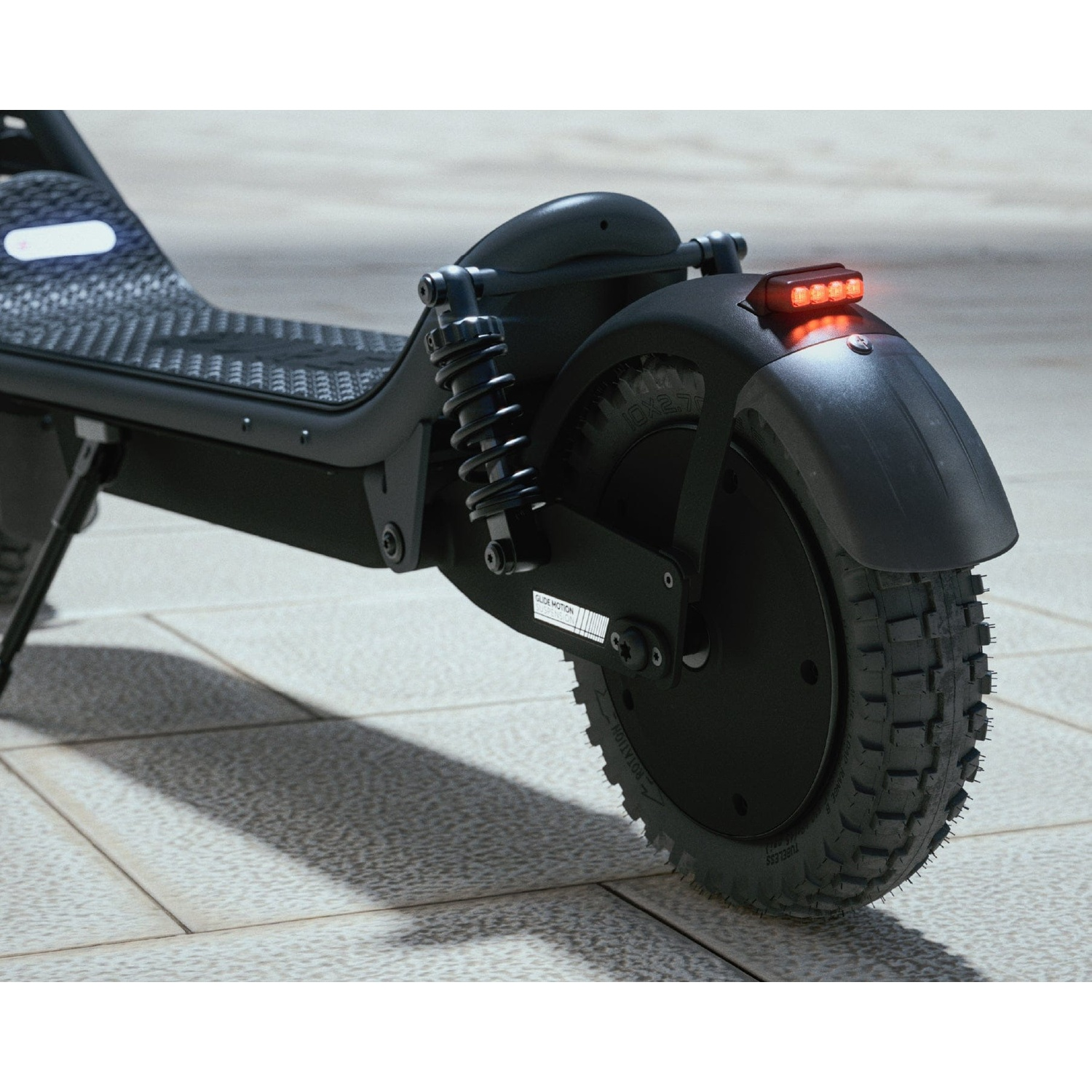 Close-up of a black electric scooter's rear wheel with suspension and an illuminated tail light.