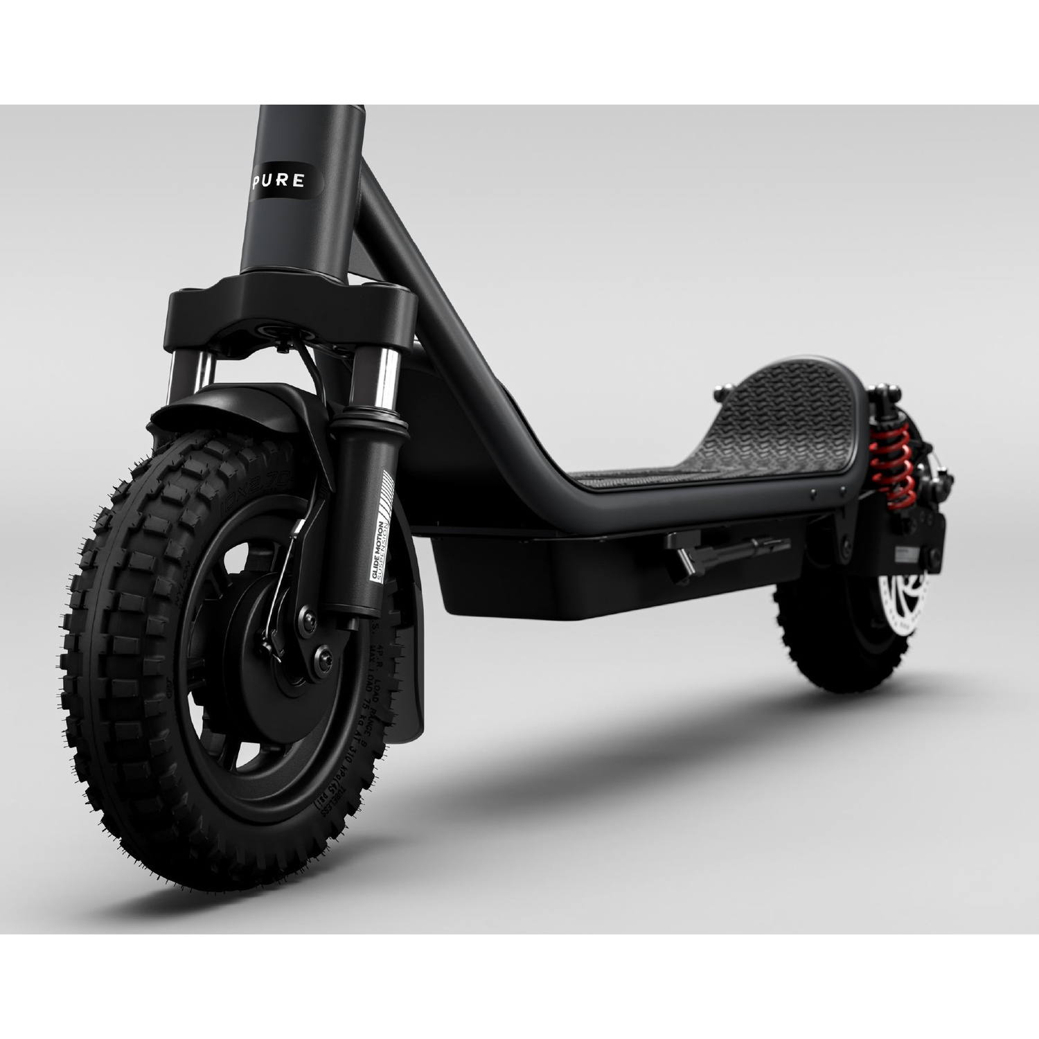 A black electric scooter with knobby tires and red rear suspension against a grey background.