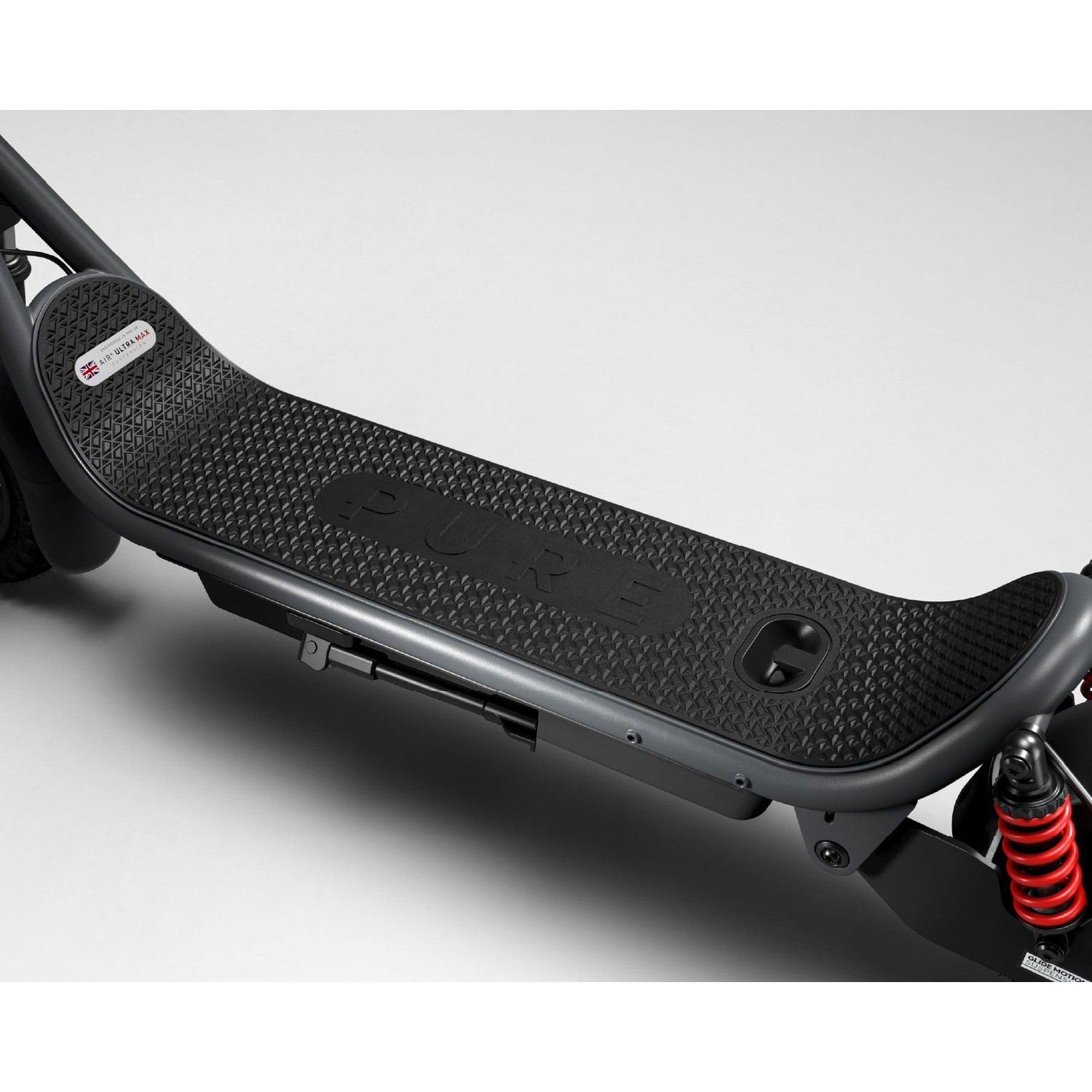 Close-up of a dark grey electric scooter deck with a textured grip mat and the word PURE embossed in the center.