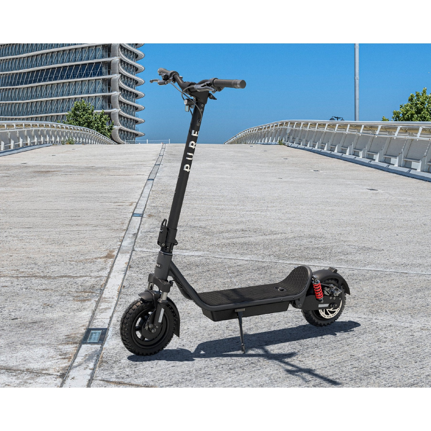 A black electric scooter stands on a concrete bridge with a modern building in the background.