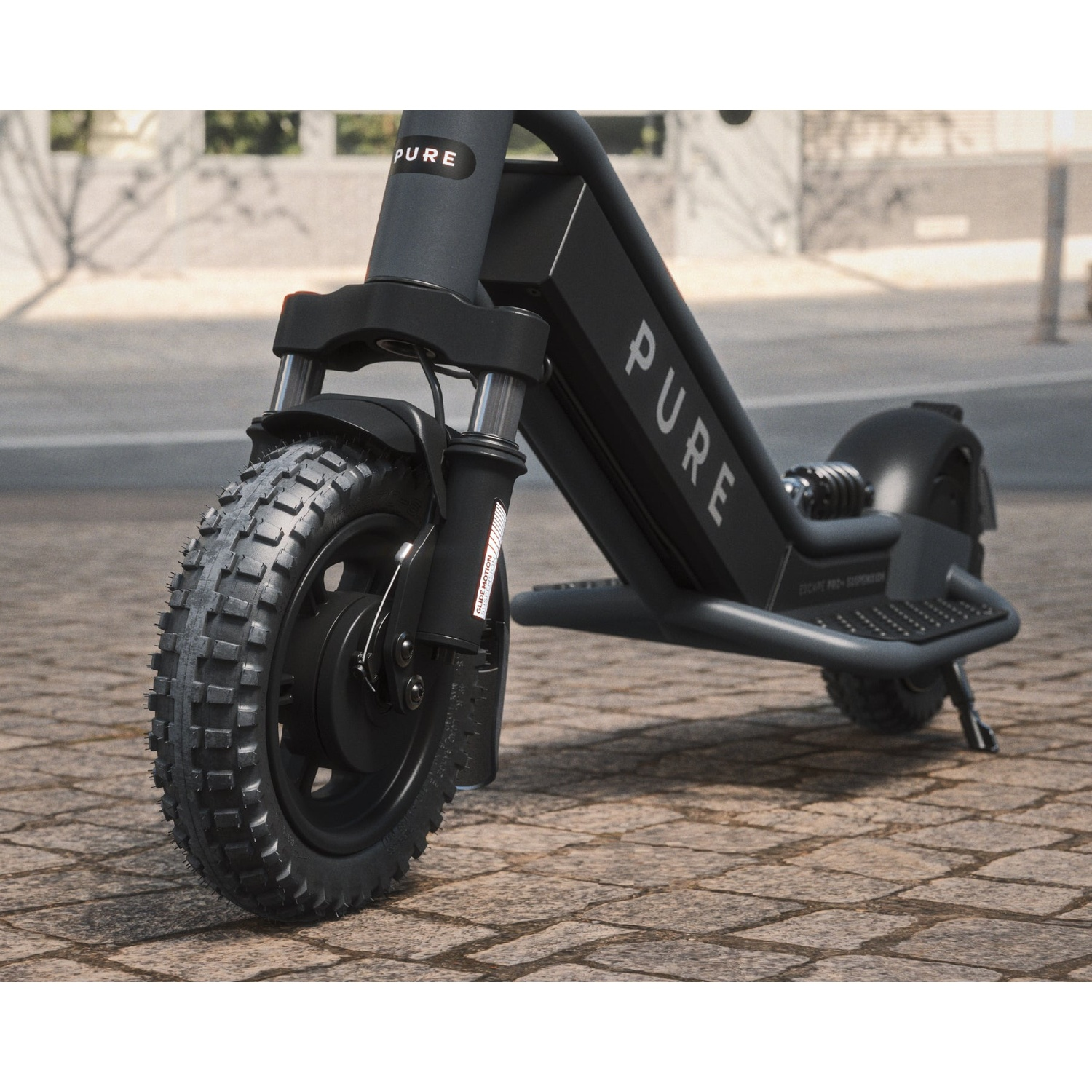 A black Pure electric scooter with knobby tires parked on a cobblestone street in a city.