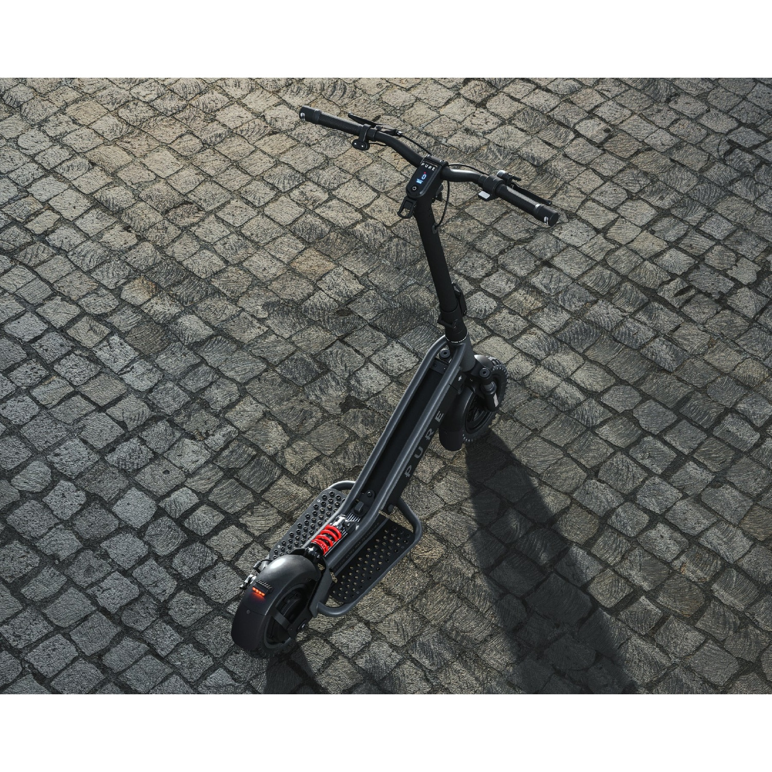 A black electric scooter parked on gray cobblestone pavement.