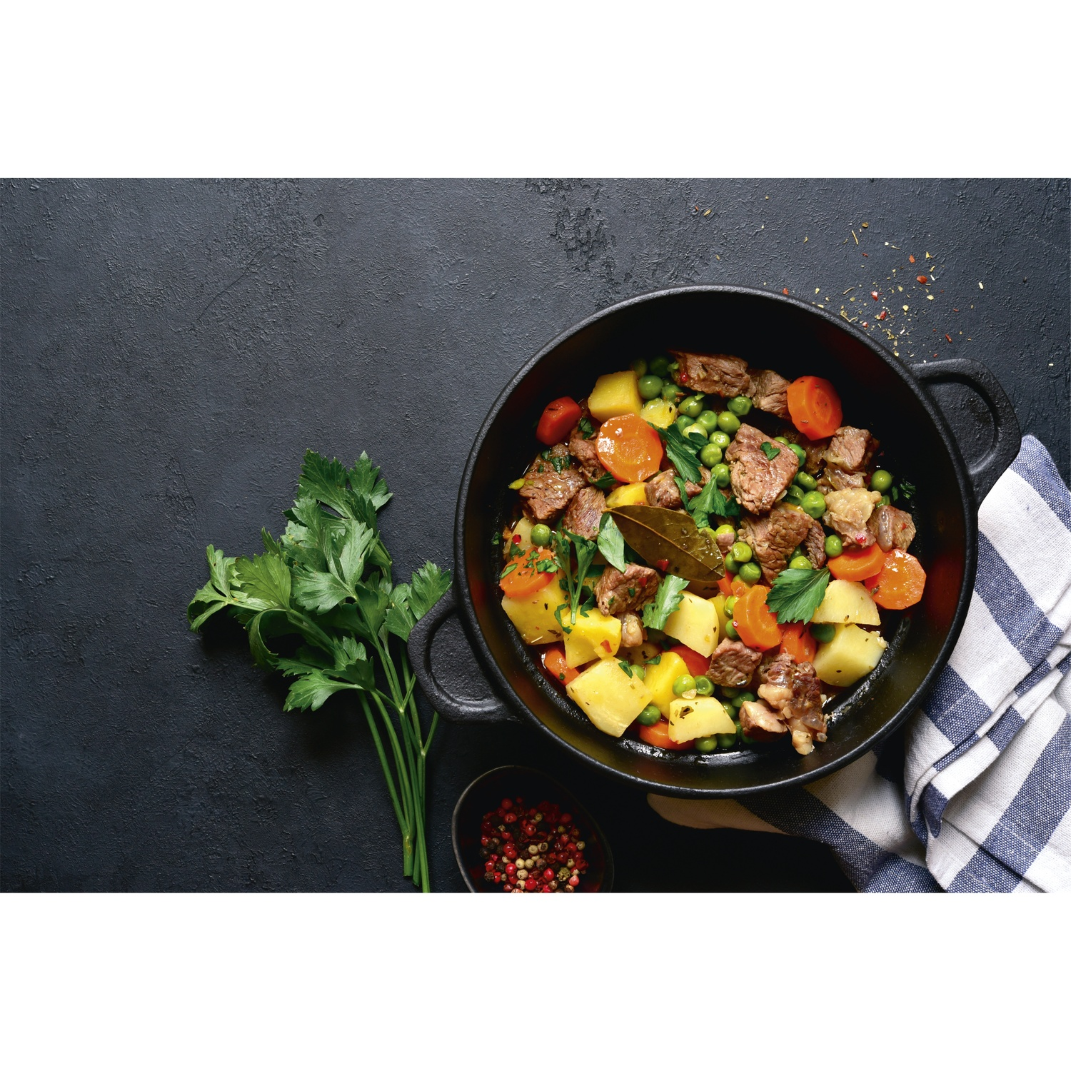 Stew with meat, potatoes, carrots, and peas in a black pot.