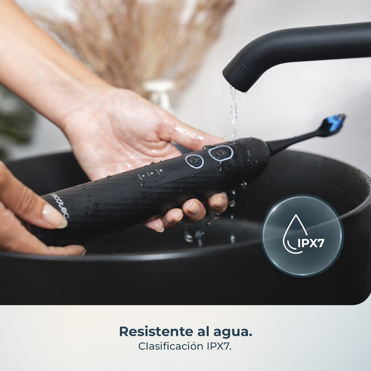 Cepillo de dientes eléctrico negro resistente al agua bajo agua corriente.