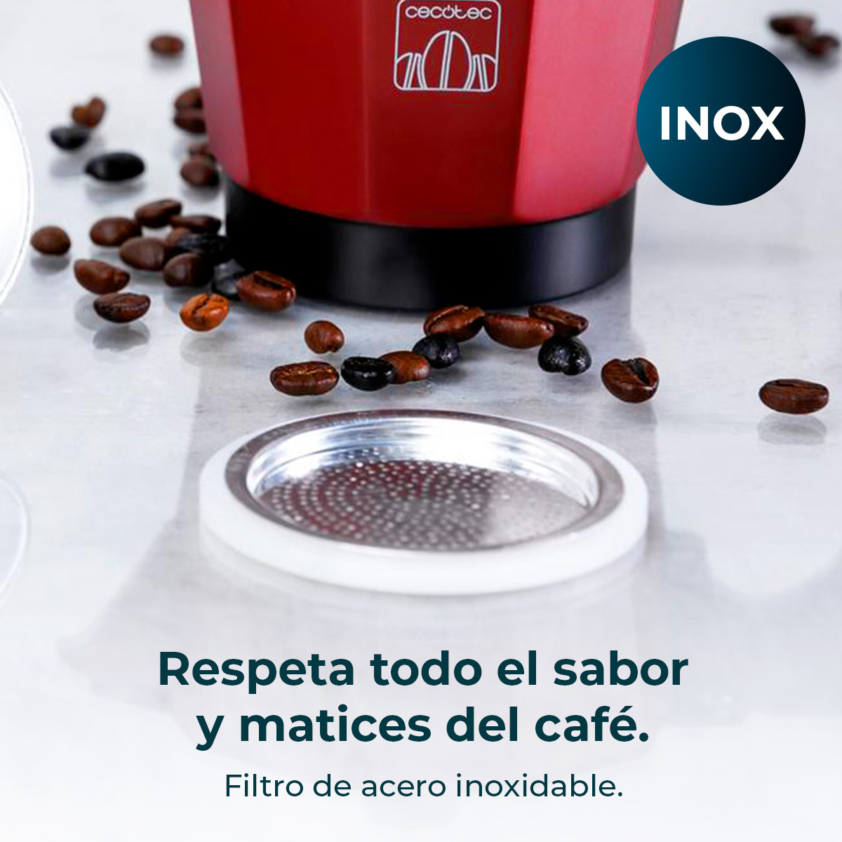 Cafetera roja con granos de café y filtro en mesa blanca.