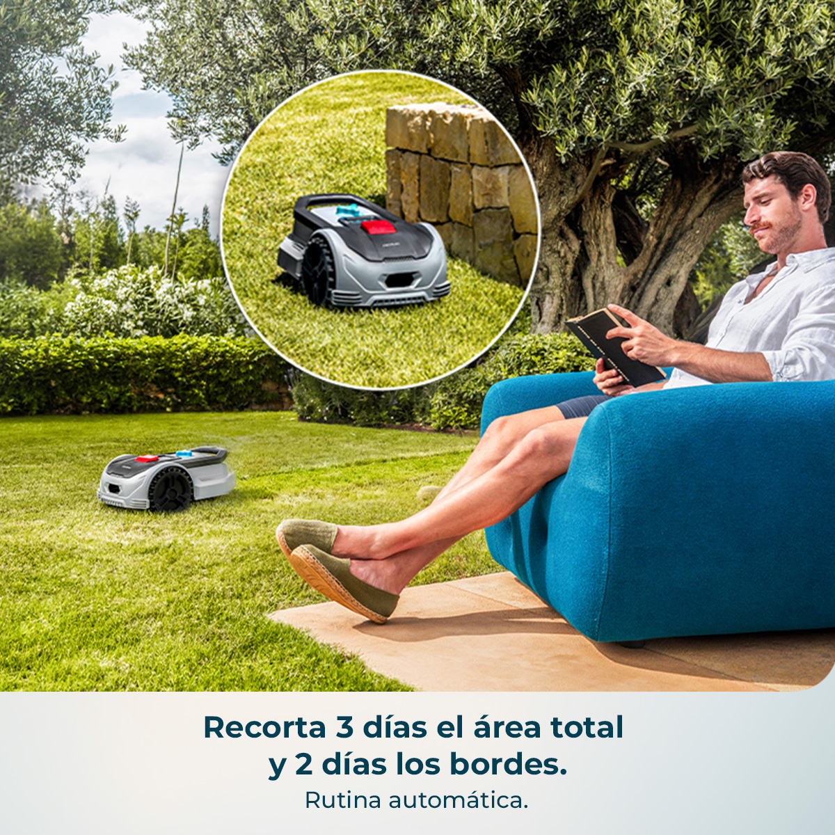 Un hombre lee un libro en un sillón azul al aire libre mientras un robot cortacésped corta el césped.