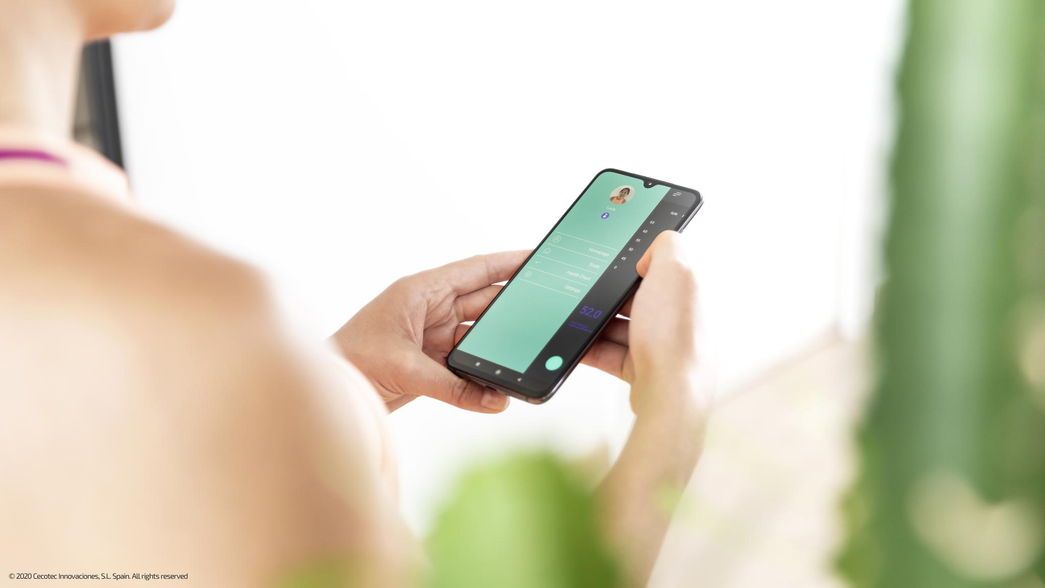 Una mujer sostiene un teléfono inteligente que muestra una interfaz de aplicación verde.
