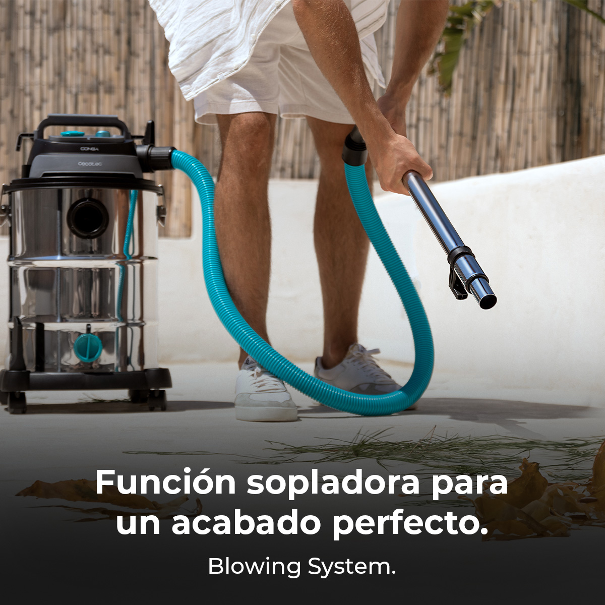 Un hombre usa una gran aspiradora en seco y húmedo con manguera azul al aire libre.