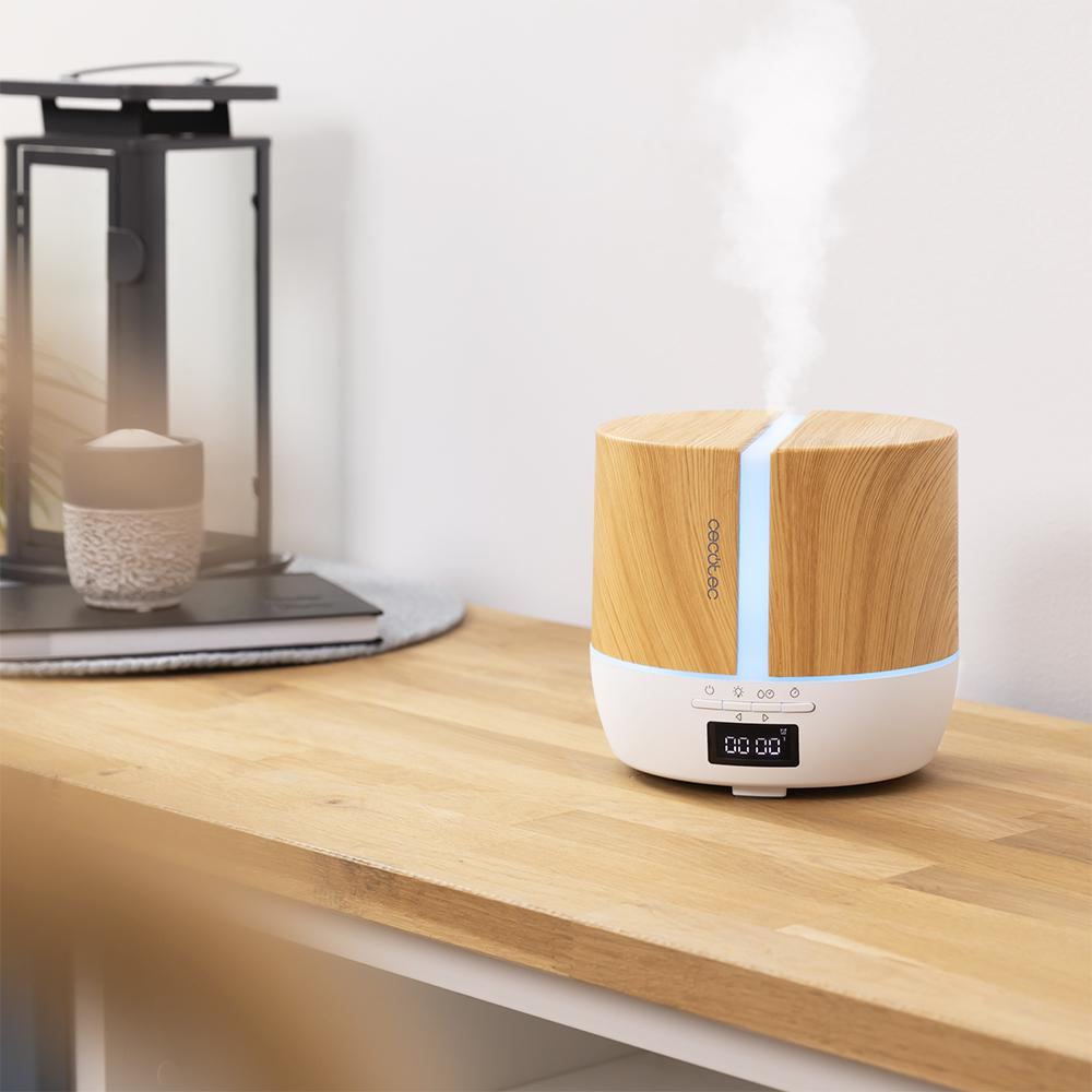 Un humidificador de madera con luz azul y vapor ascendente se encuentra sobre una mesa.